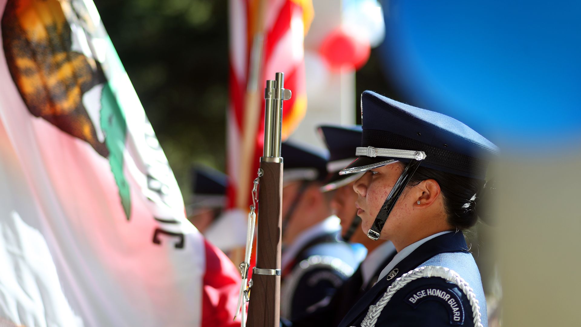 Photo of military service members standing at attention next to American and Californian flags