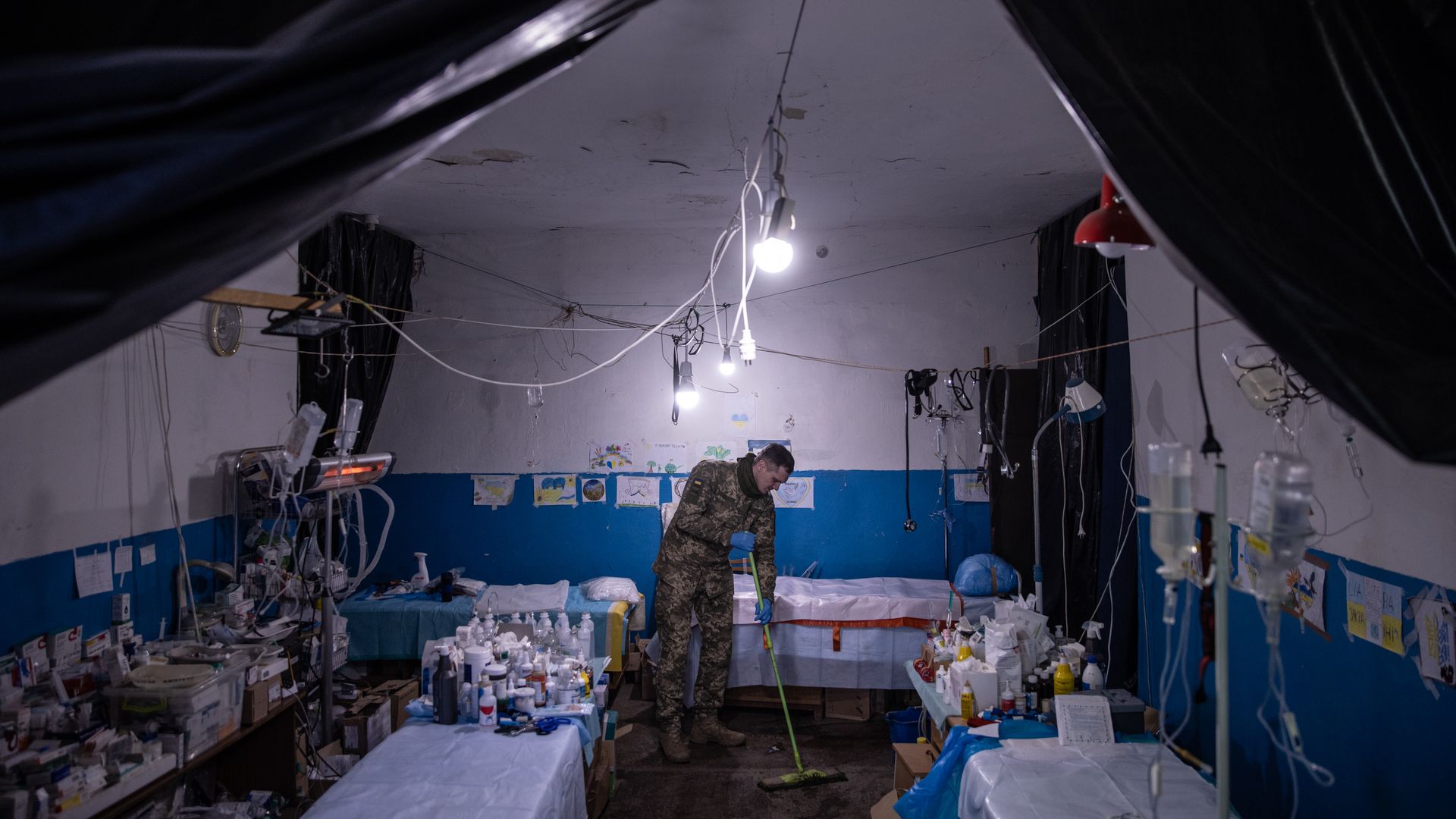 A Ukrainian military medic cleans the floor of the small operating room