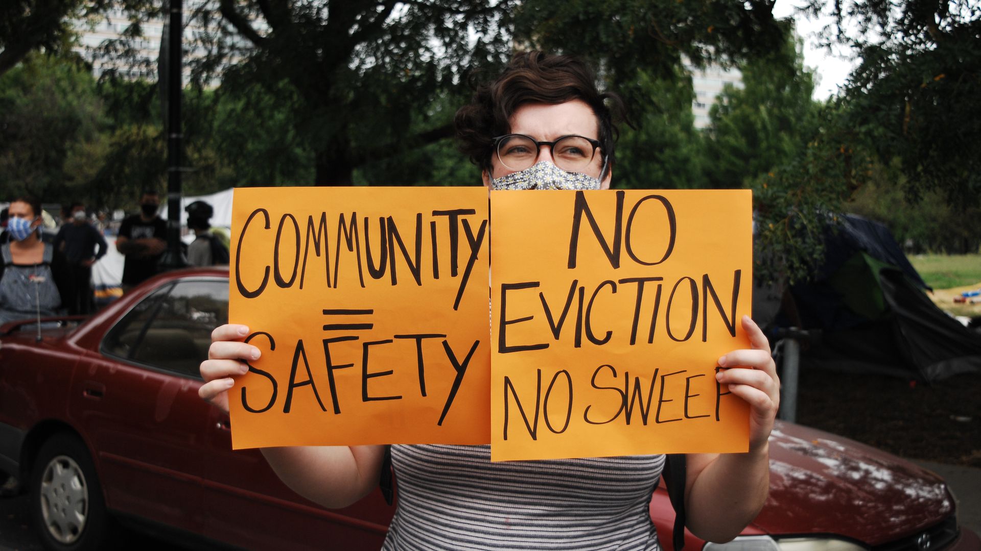 A protestor holding signs calling for a halt to evictions.