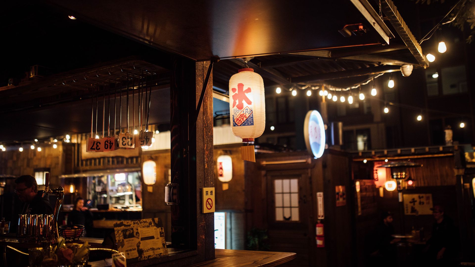 A Japanese latern hangs near a dimly lit bar