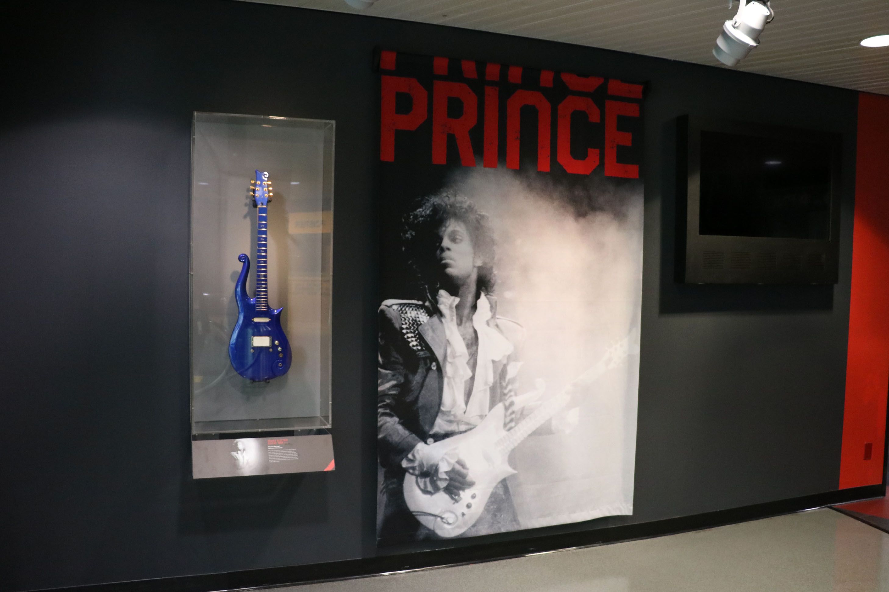 Prince's blue guitar encased next to a poster of the rock star inside the Rock & Roll Hall of Fame. 