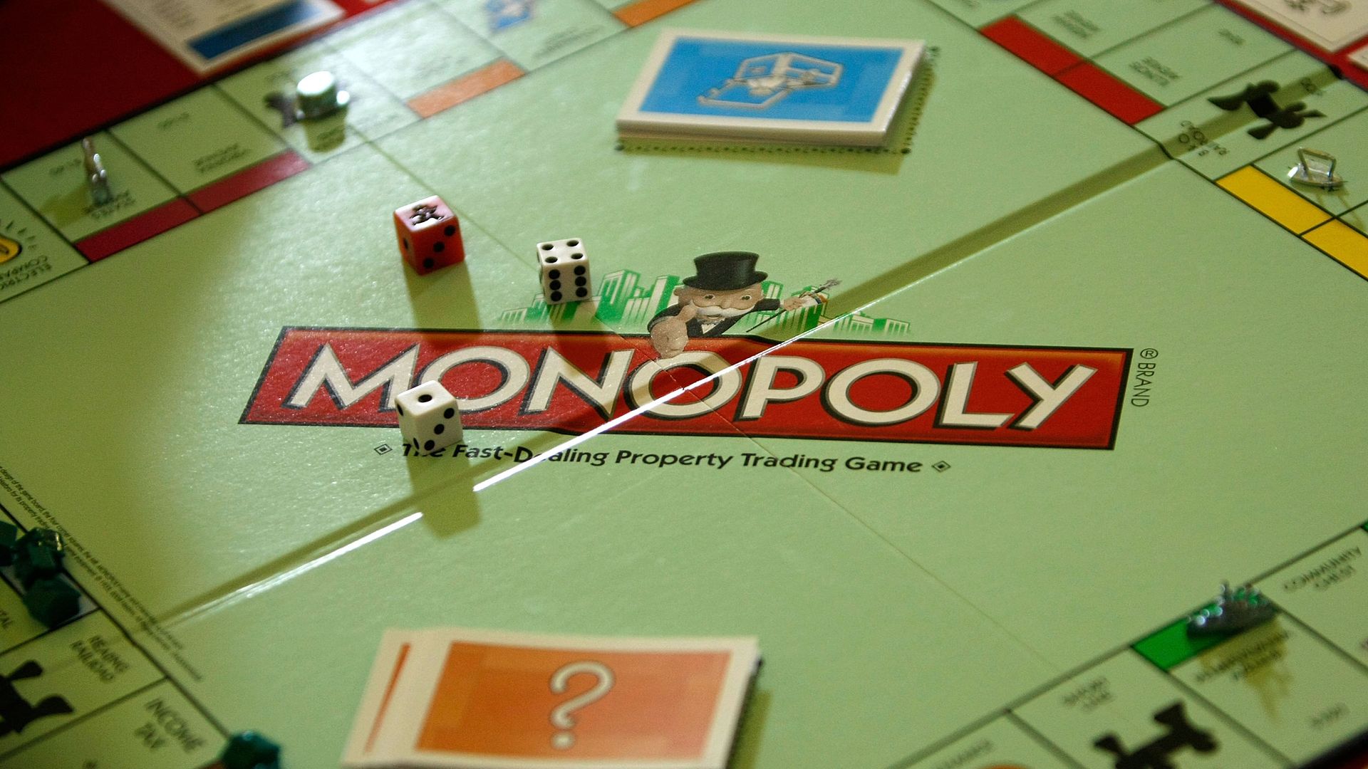 A close-up of a Monopoly board with dice, game pieces and Chance and Community Chest cards.