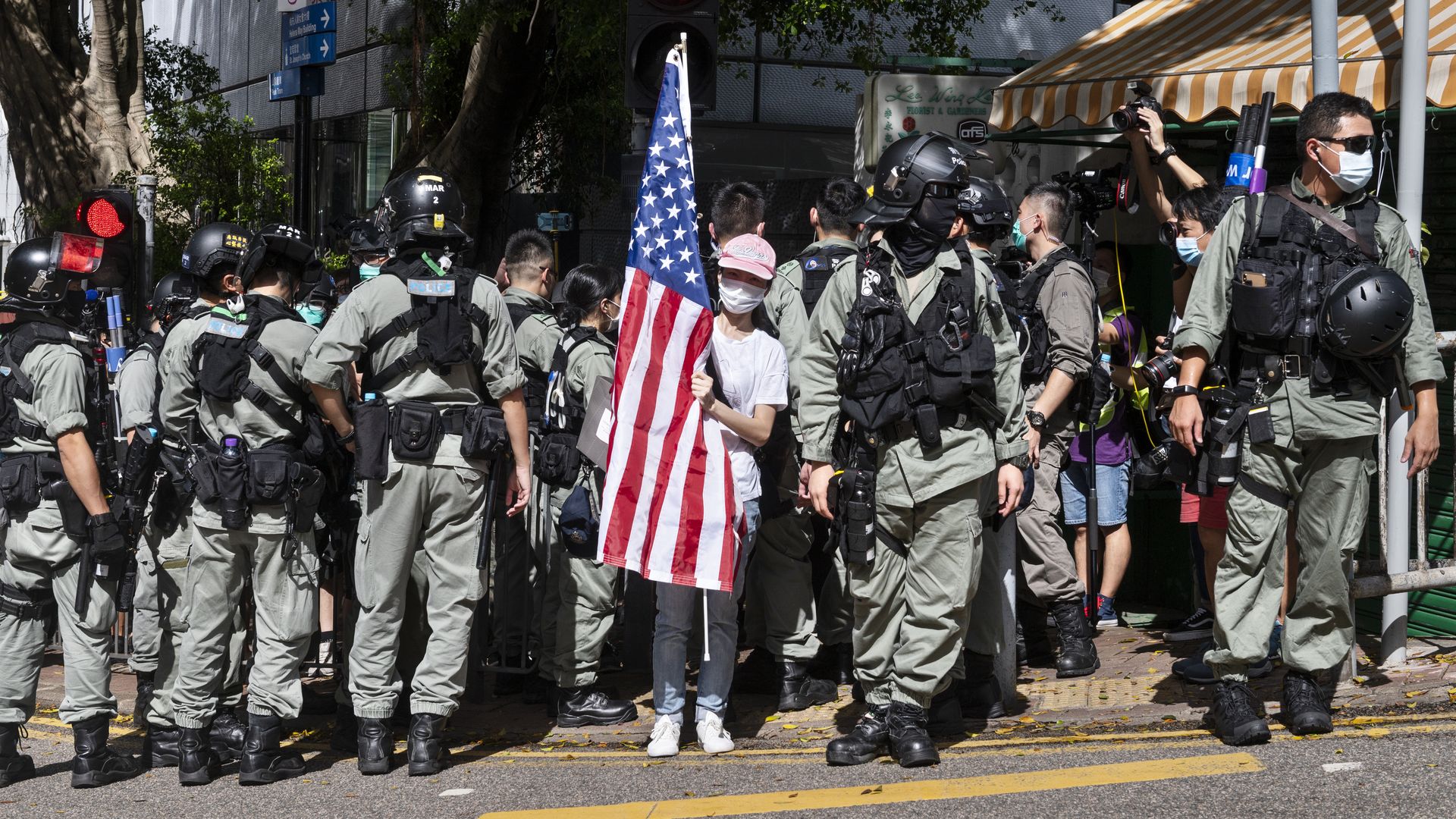 Police officers surround a woman holding an US flag during a march to celebrate US Independence Day outside the US consulate in Hong Kong on July 4