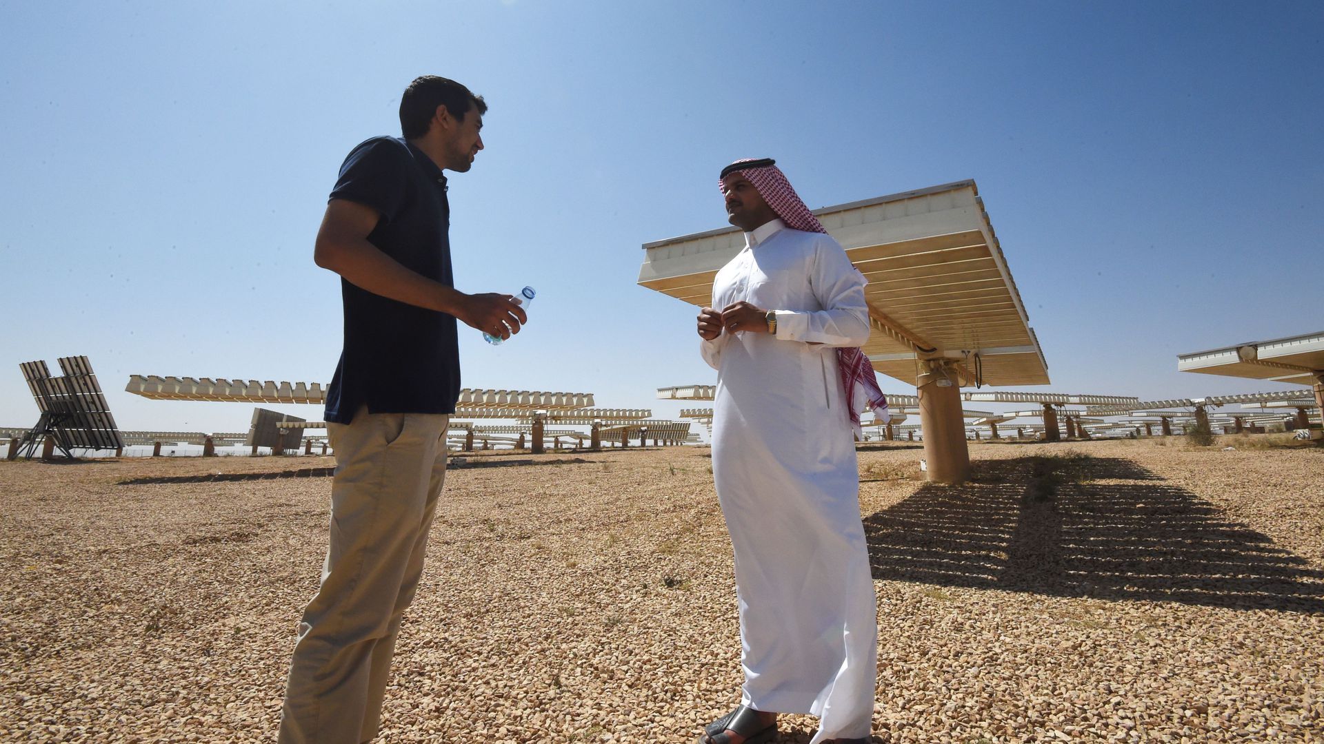 A Saudi man speaks to a journalist near a solar panel field outside
