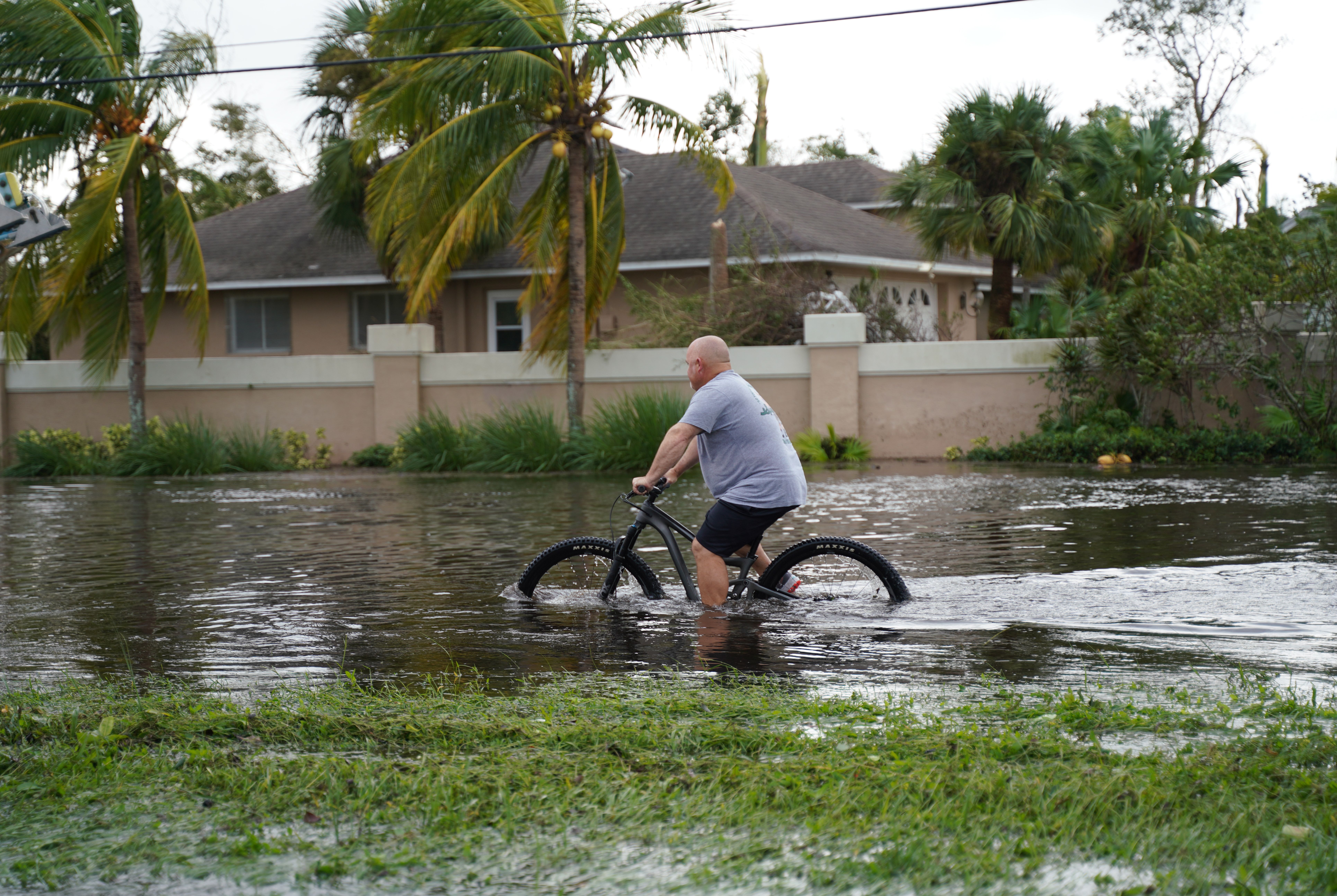 man biking through a flooded street in Florida