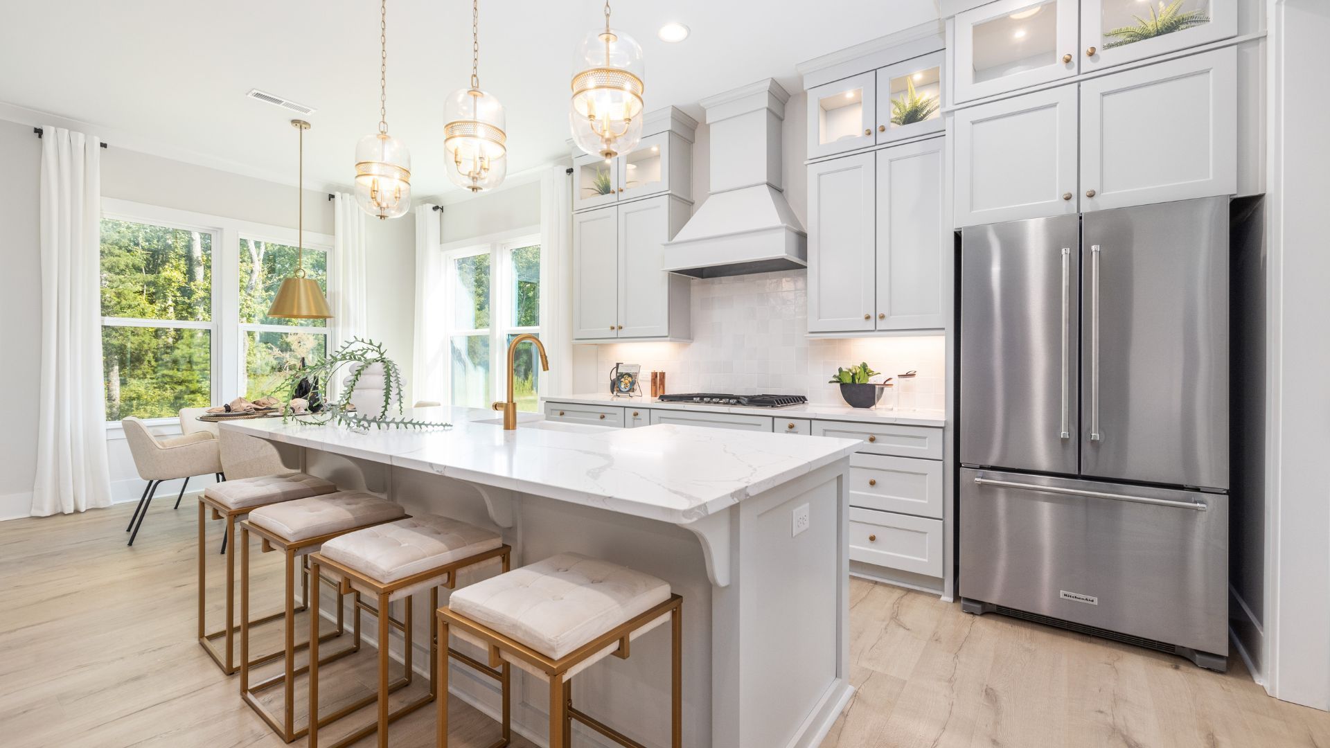 Bright kitchen with white cabinets, marble island, and gold accents.
