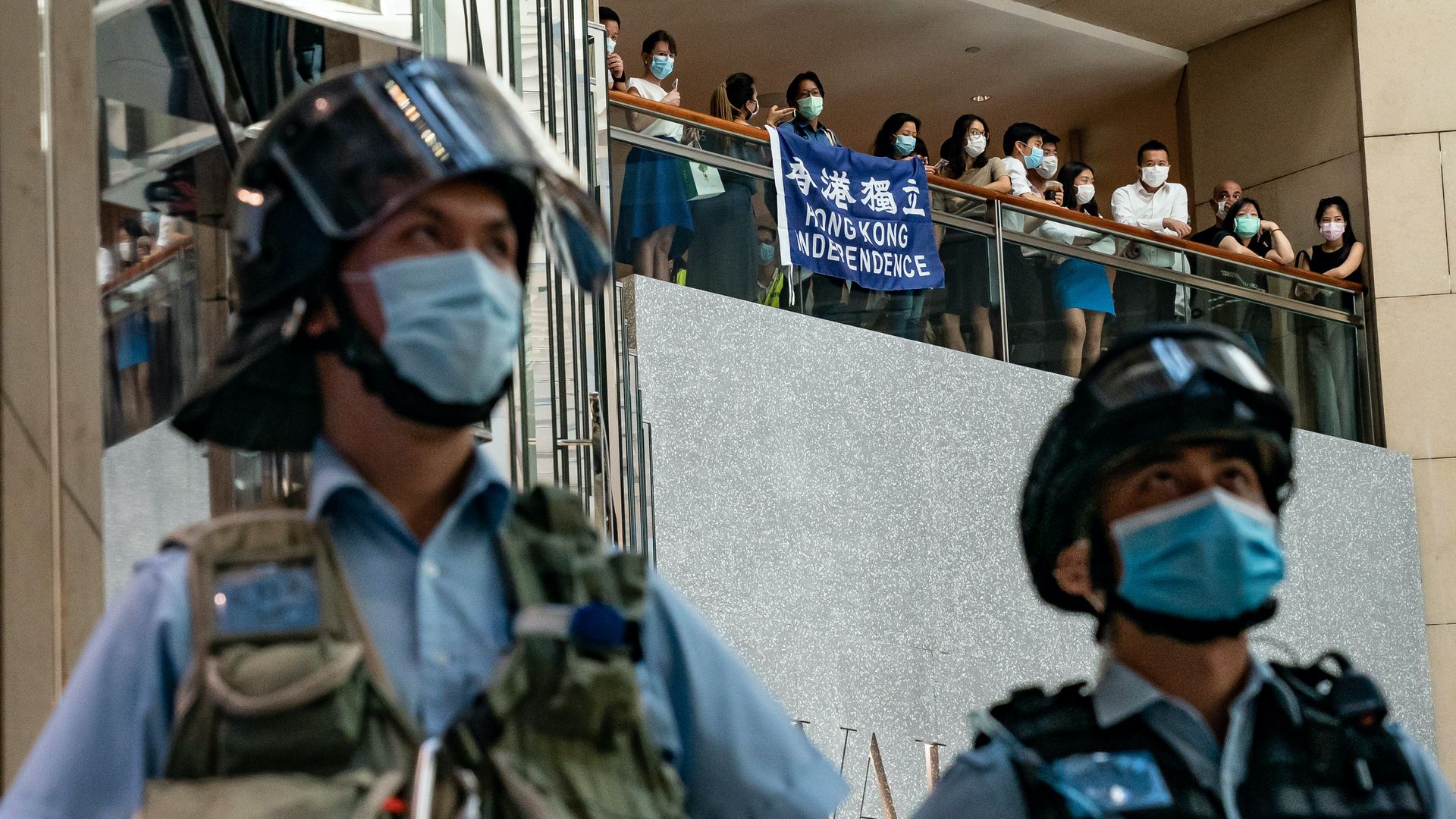 Pro-democracy supporters hold a Hong Kong Independence flag and shout slogans during a rally against the national security law as riot police secure an area in a shopping mall on June 30 in Hong Kong