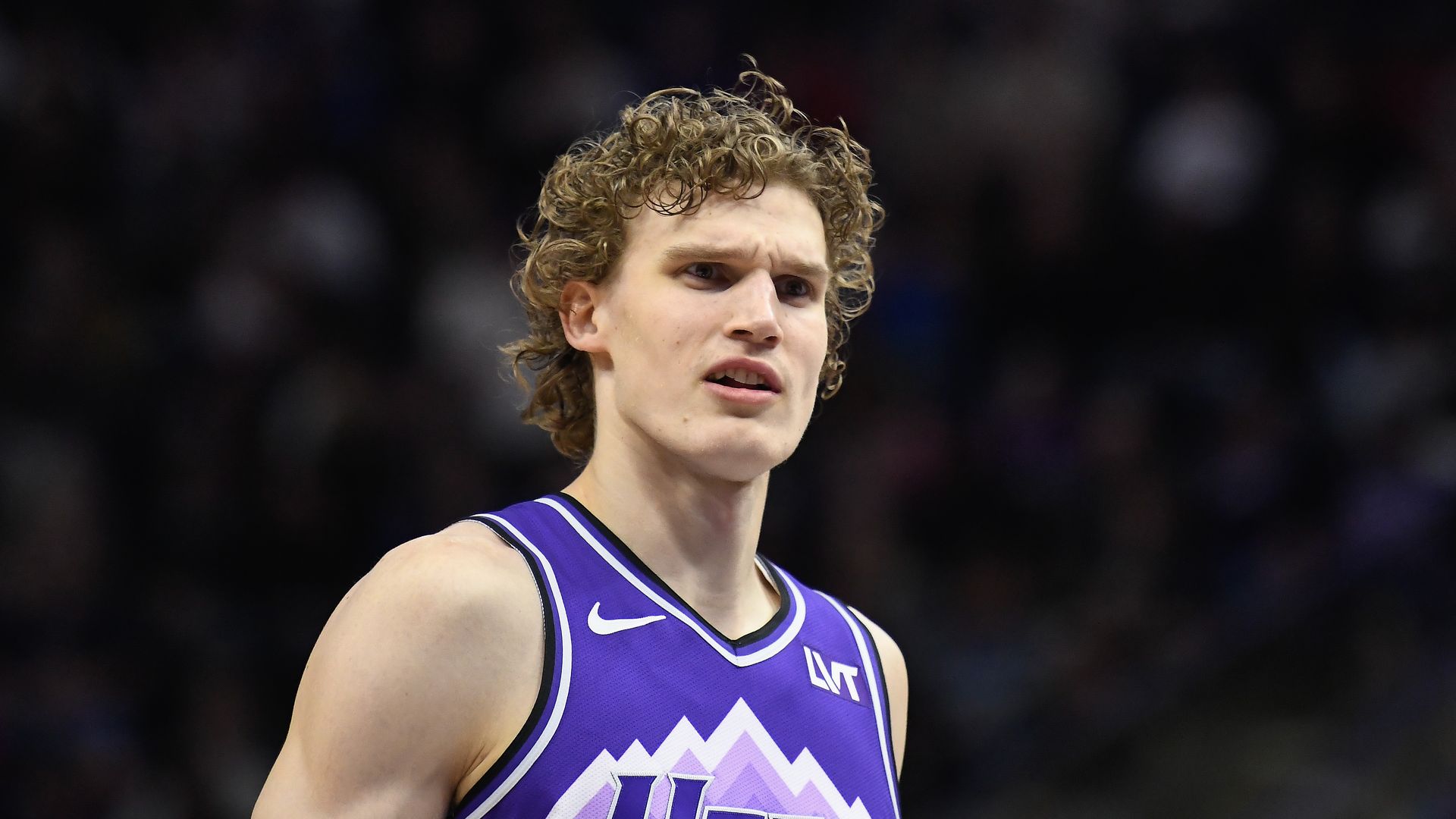 A man in a purple uniform looks ahead intently