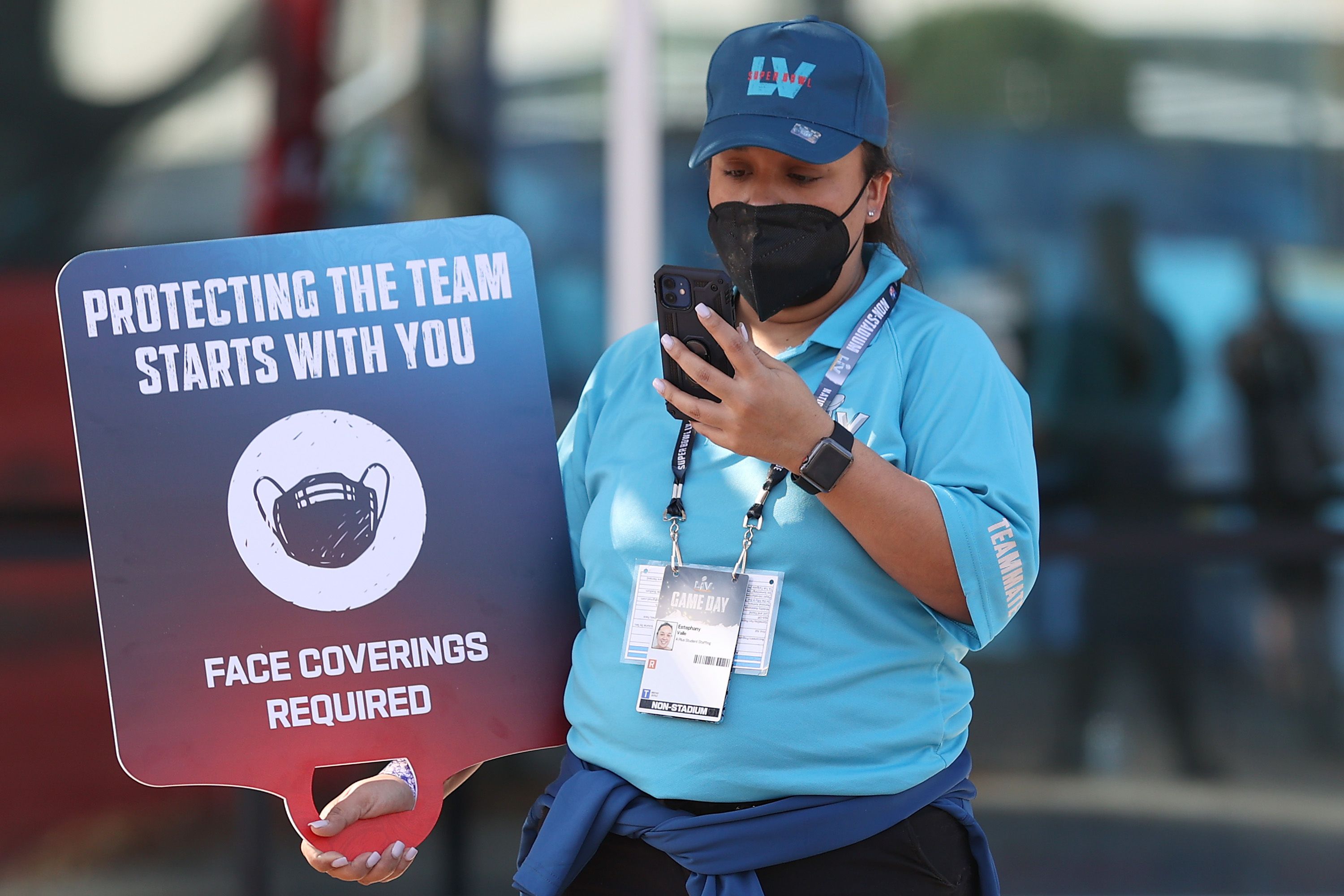 A worker holds a 'face coverings required' sign before Super Bowl LV between the Tampa Bay Buccaneers and the Kansas City Chiefs at Raymond James Stadium on February 07, 2021 in Tampa, Florida.