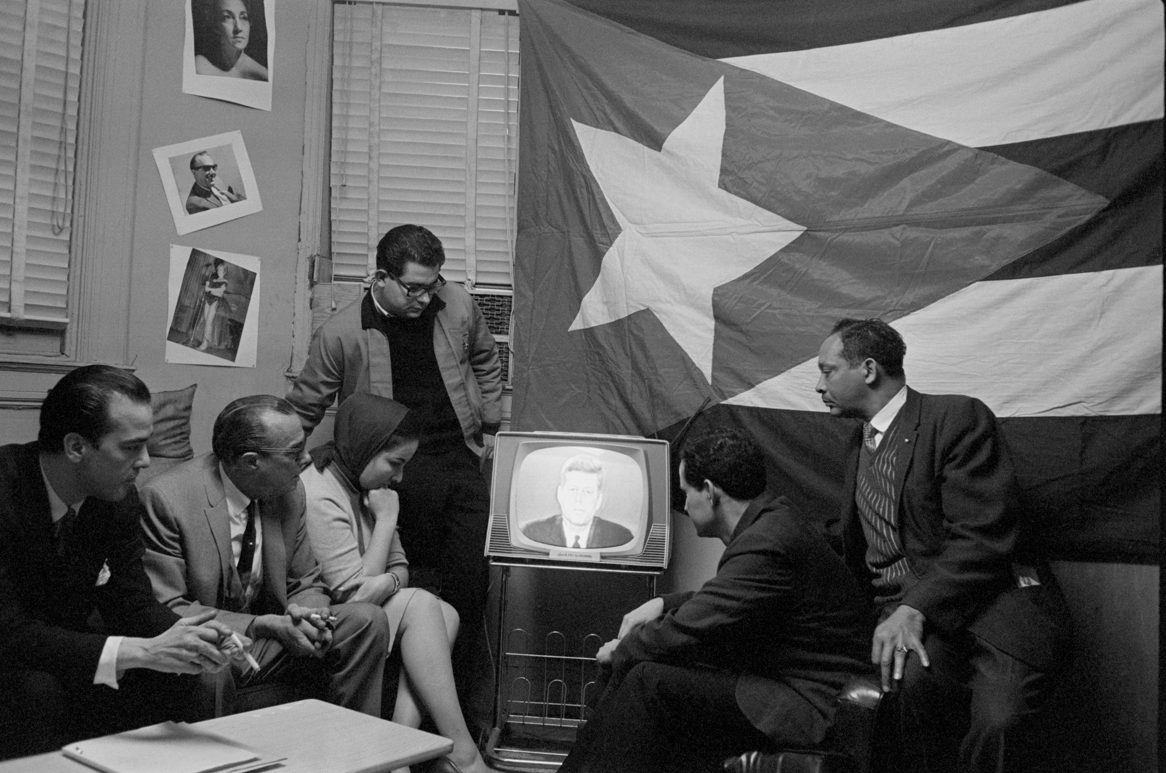 A group of Cuban refugees in Manhattan watch President Kennedy delivering a speech on television during the Cuban Missile Crisis with the Soviet Union.