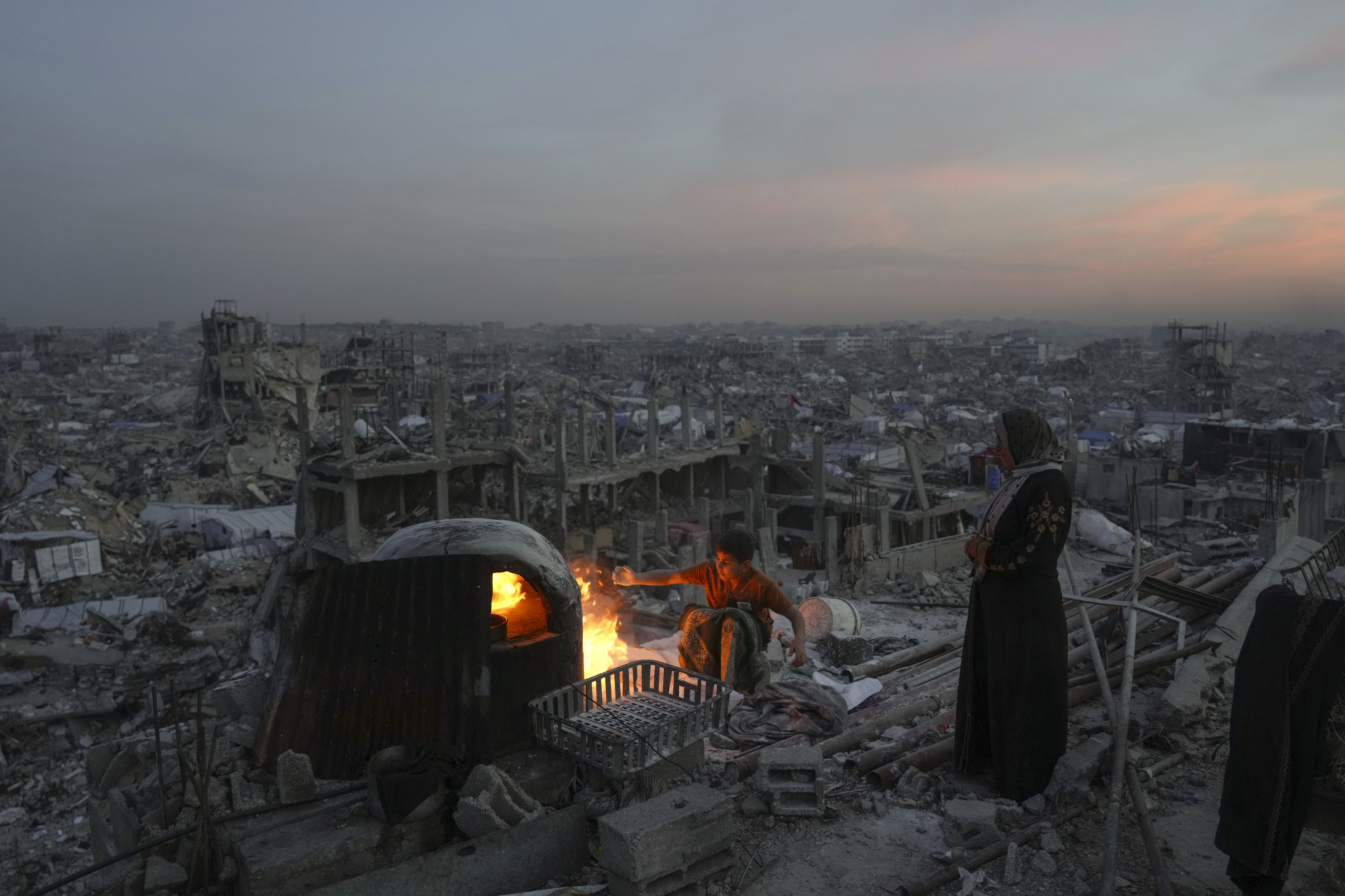 Palestinians Ali Marouf and his mother Aisha cook on fire on the roof of their destroyed house by the Israeli army's air and ground offensive in Jabaliya, Gaza Strip, on Monday, March 17, 2025. (AP Photo/Jehad Alshrafi)