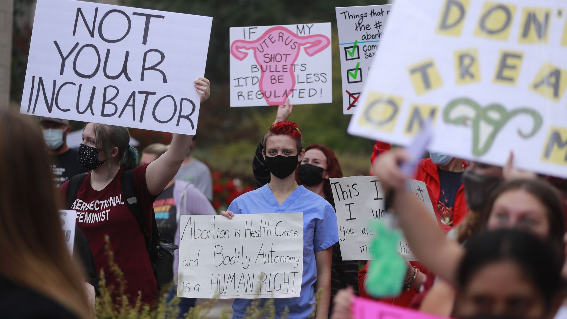 Photo of pro-abortion protesters holding up placards and signs at an outdoor demonstration