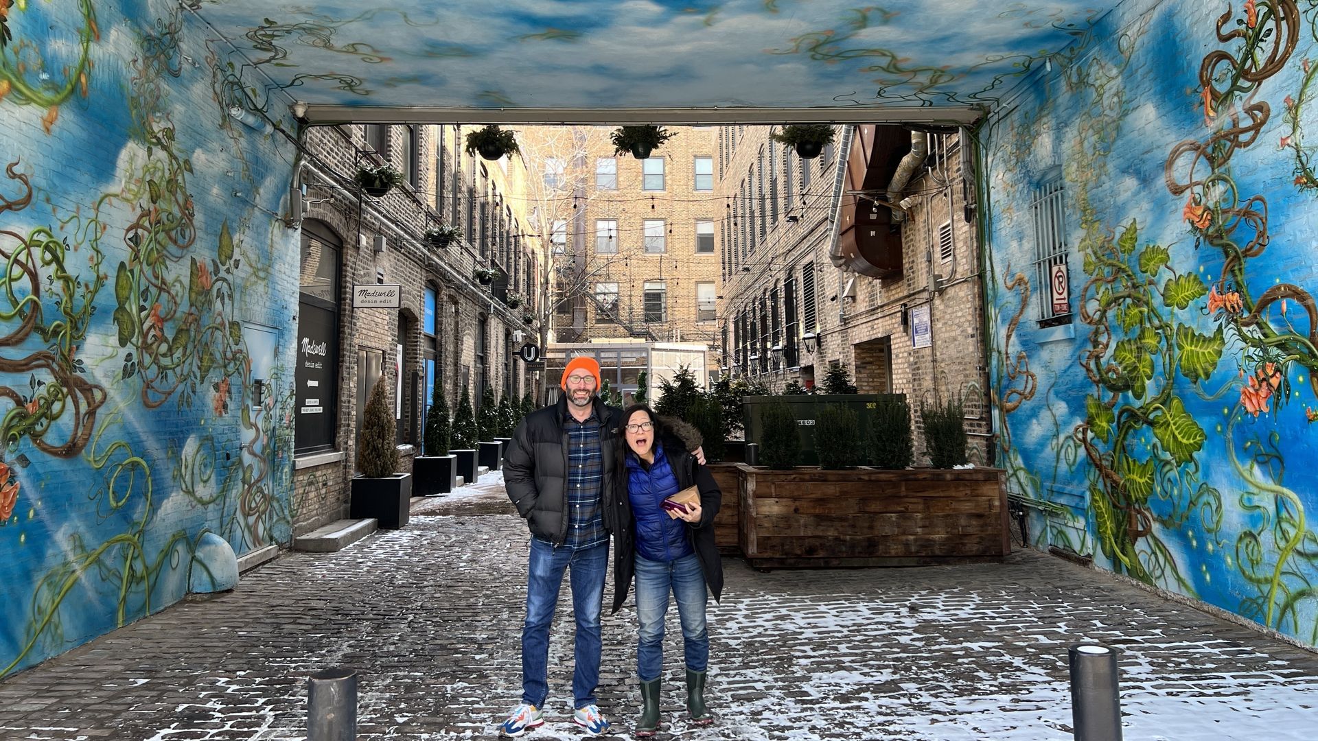Photo of two people standing in an painted alleyway. 