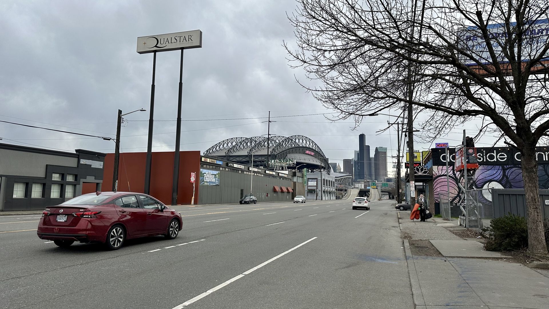 A red car drives on a road with T-Mobile park in background.