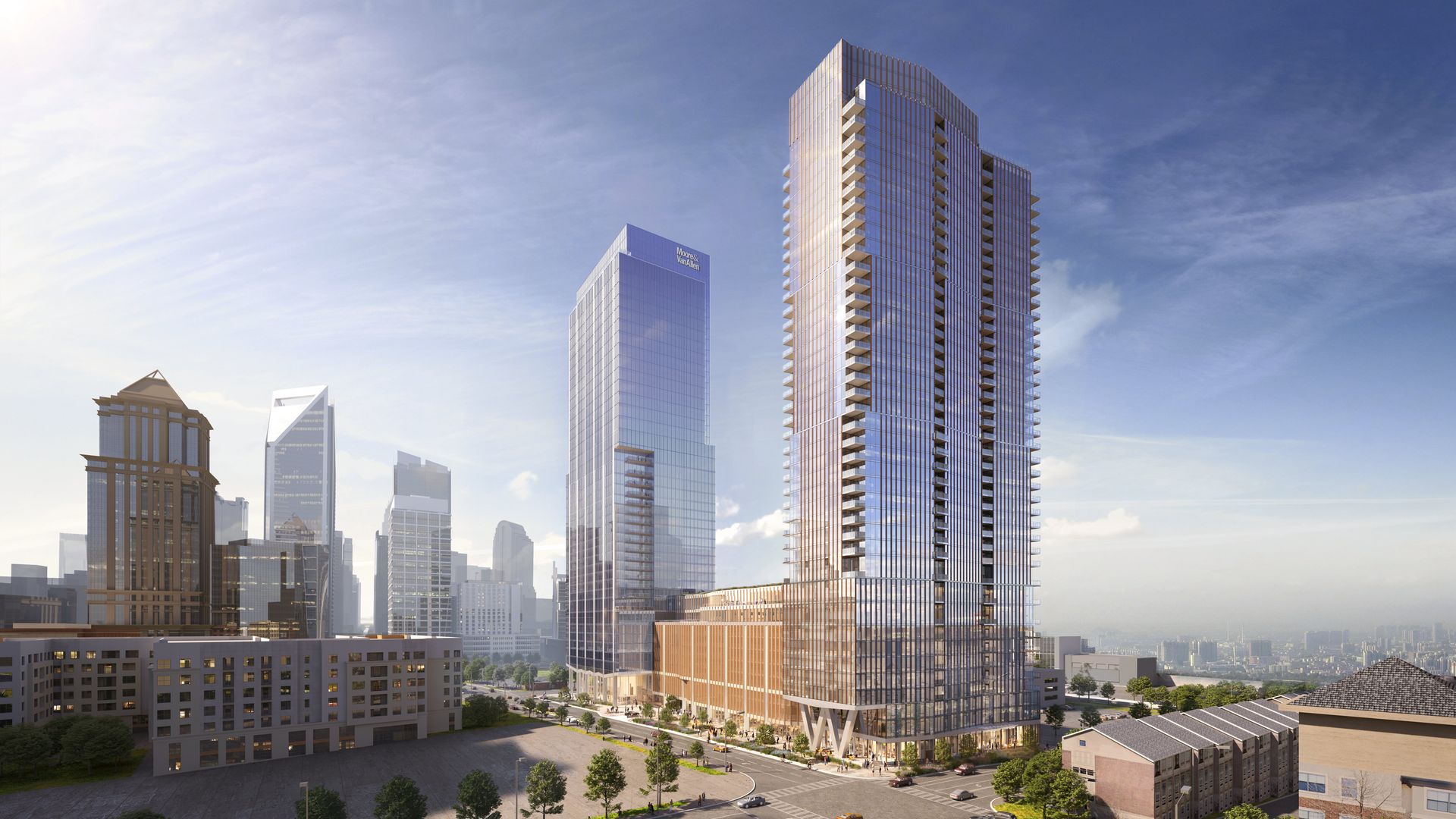 High-rise modern buildings with glass facades in a cityscape under a partly cloudy blue sky, surrounded by streets, trees, and smaller structures.