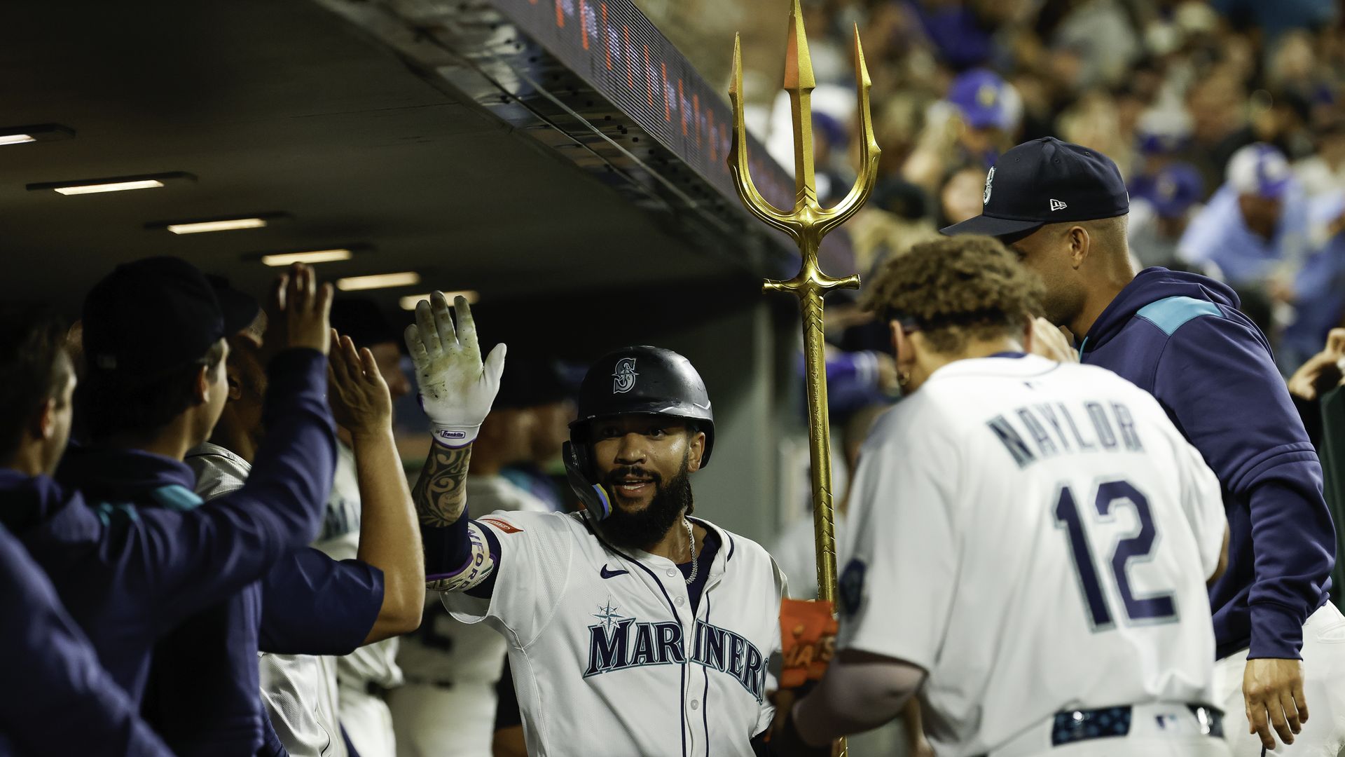 A pro baseball player holds a neptune and raises a hand in celebration after a win. 