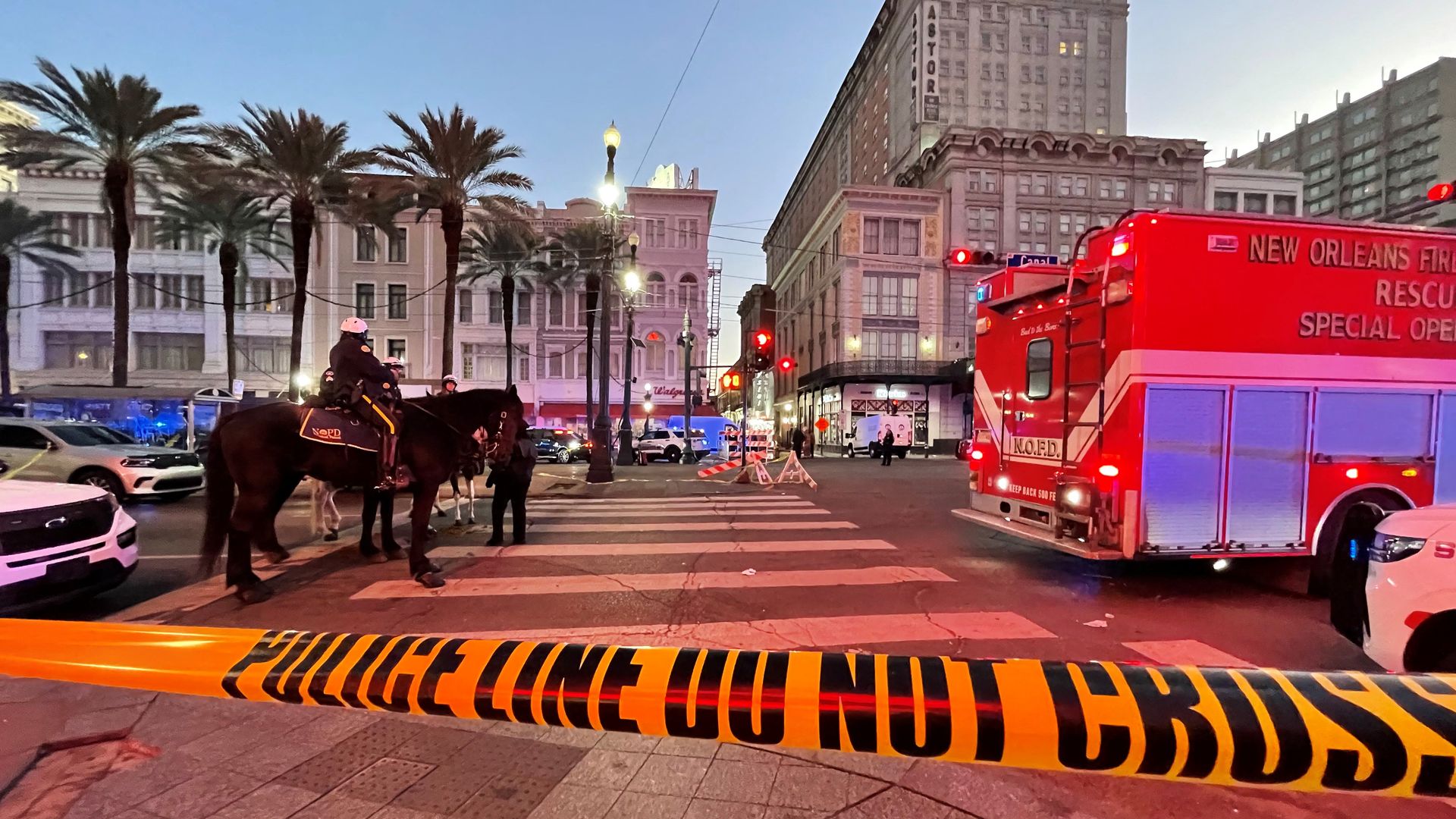 Yellow tape that says "Police Line Do Not Cross" is in the foreground, with a mounted officer behind the tape and emergency vehicles at the site of the New Orleans terrorist attack Jan. 1.