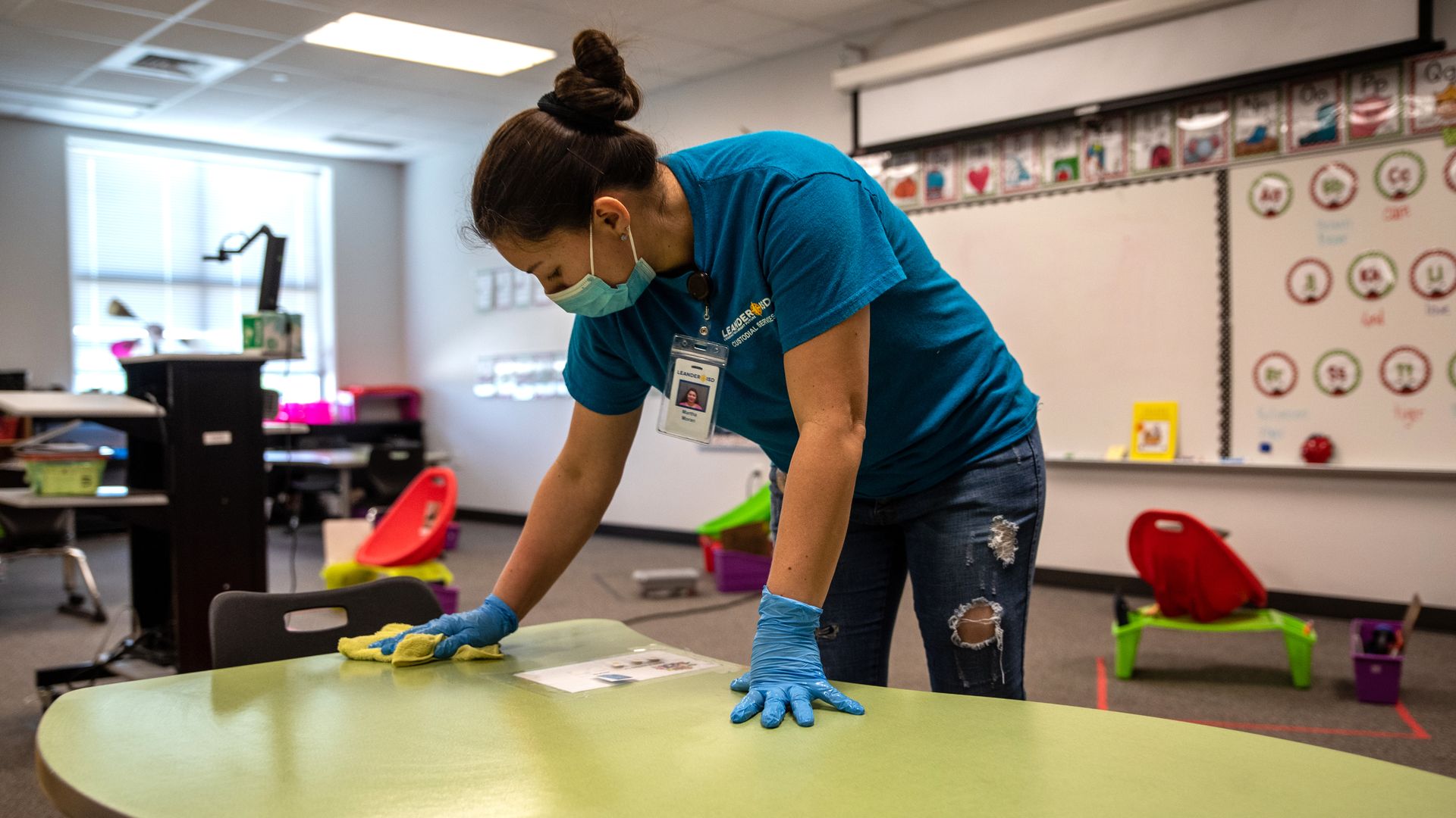 A worker cleans a desk in a classroom.