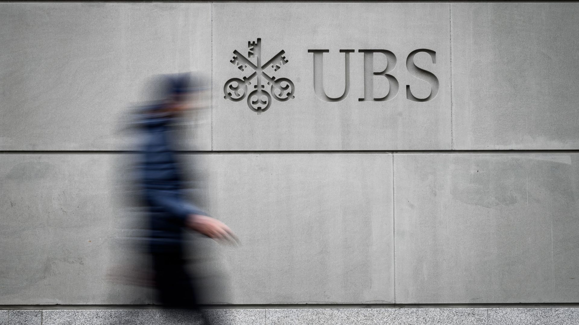 A pedestrian walks by the logo of Swiss banking giant UBS.