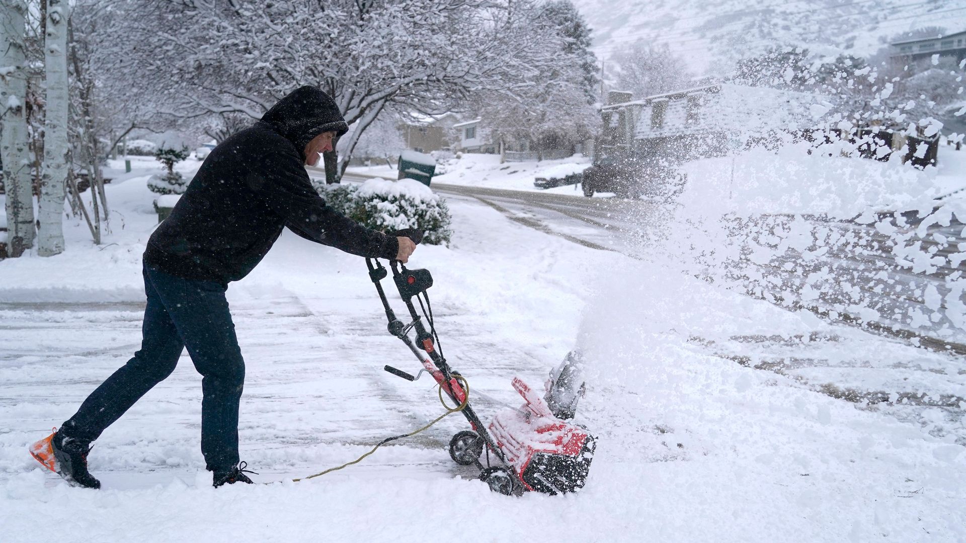 A man clears his driveway of snow from an overnight storm in Provo, Utah, on December 13, 2022. 