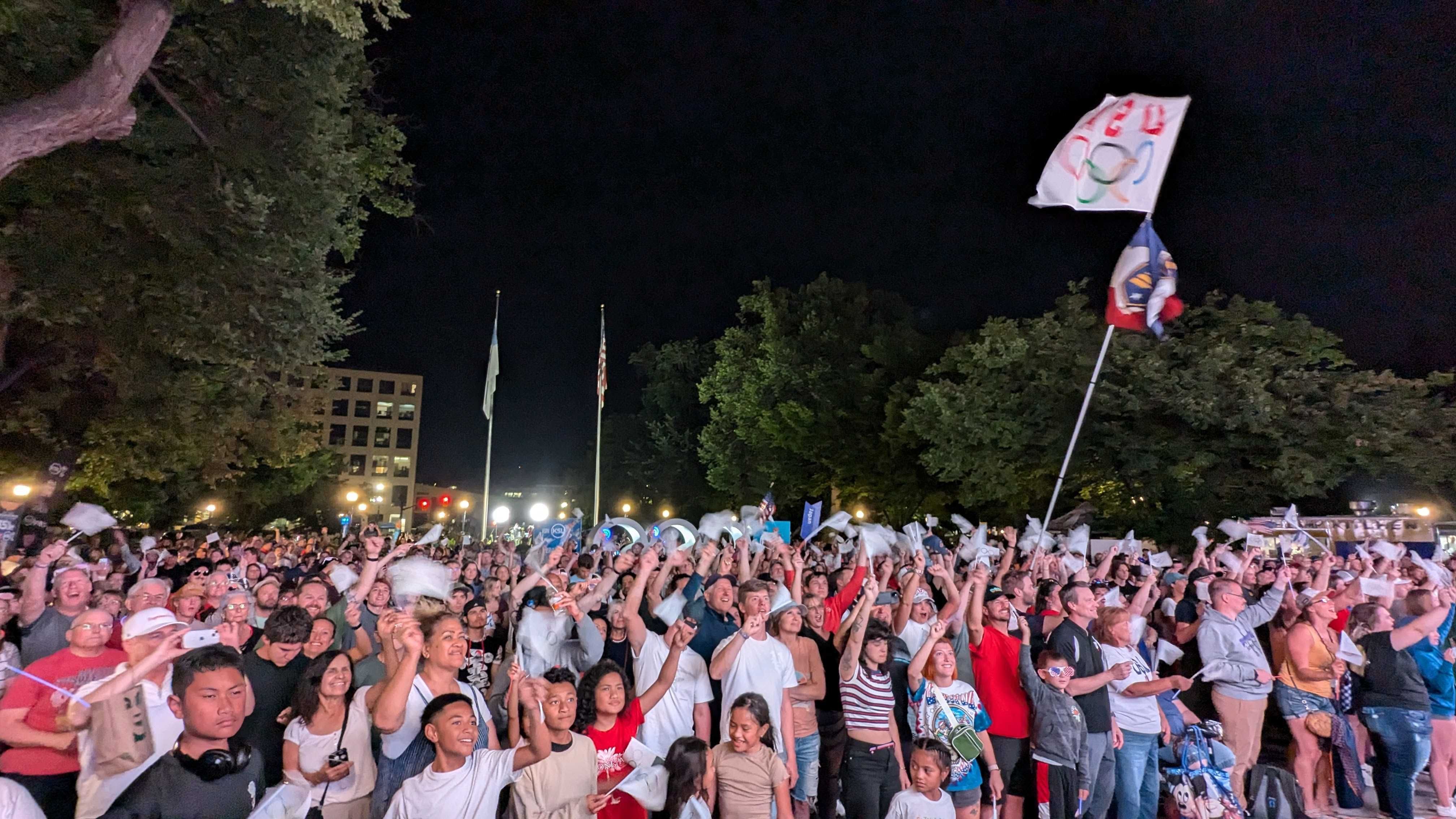 A crowd of people waving flags at night outside and celebrating