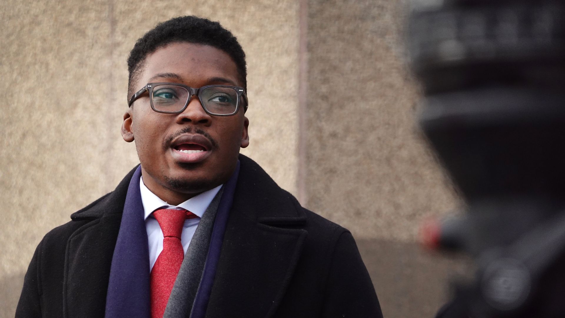 Photo of a man speaking at a press conference. 