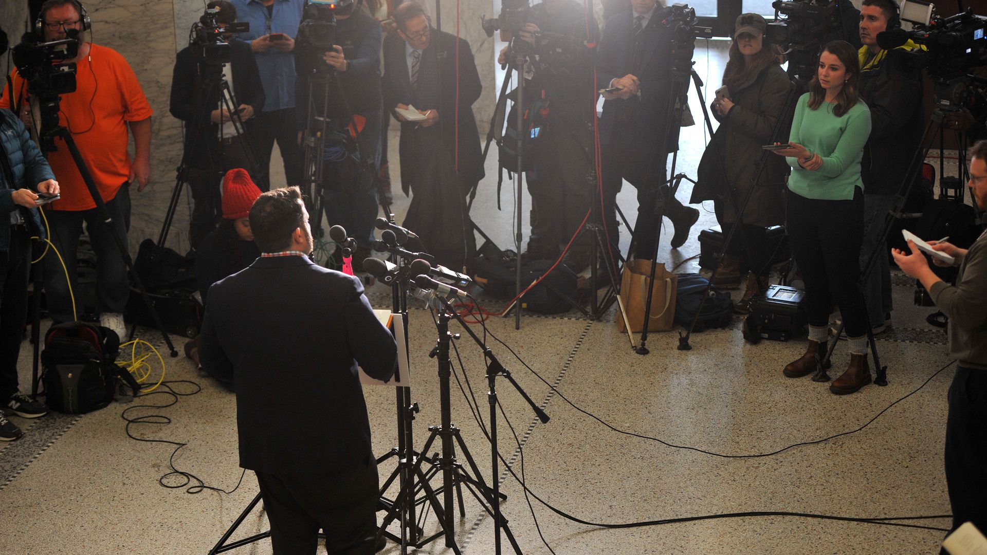 In this image, Troy Price stands in front of a crowd of reporters