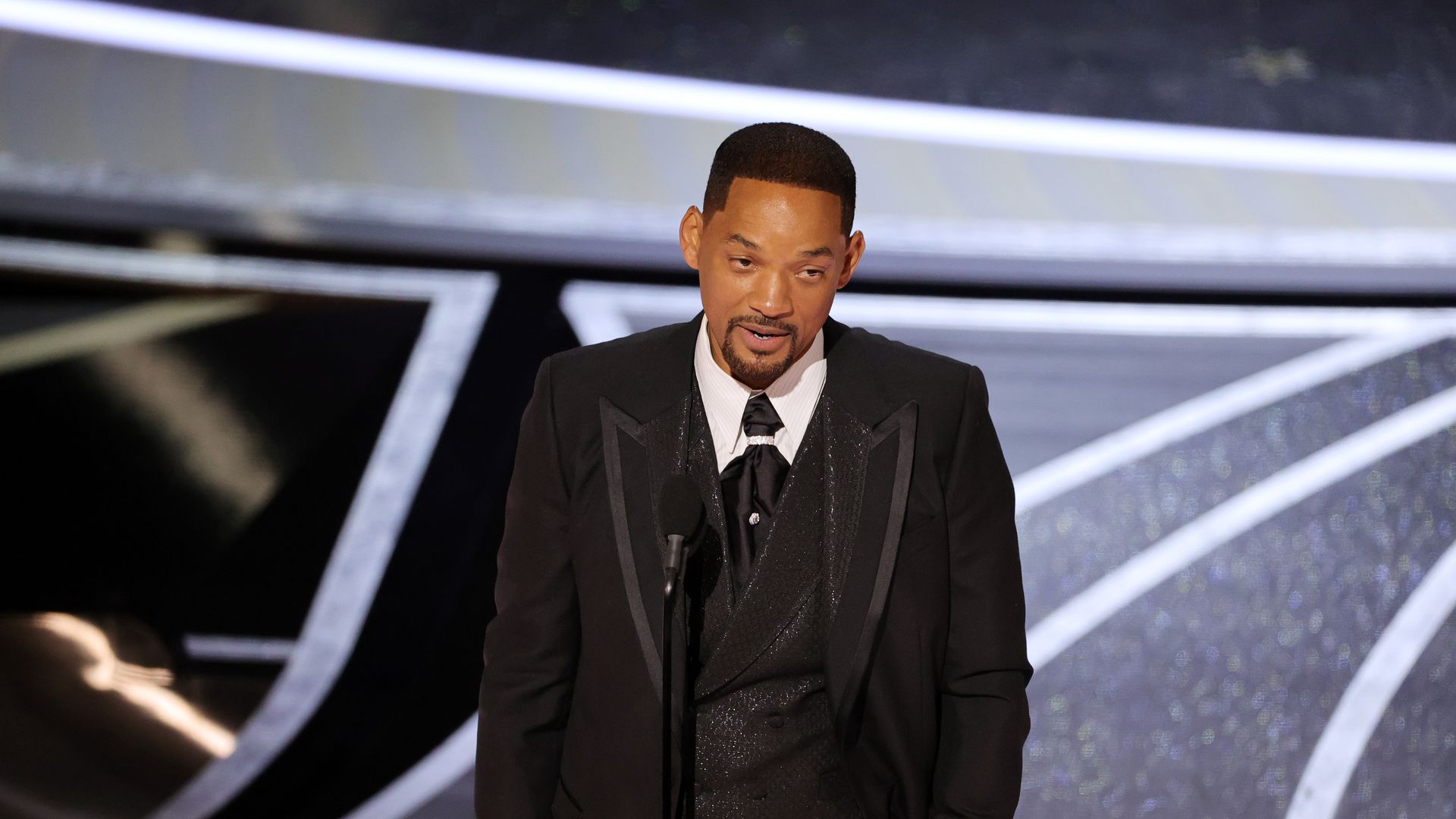 Photo of Will Smith speaking into a mic on a stage 