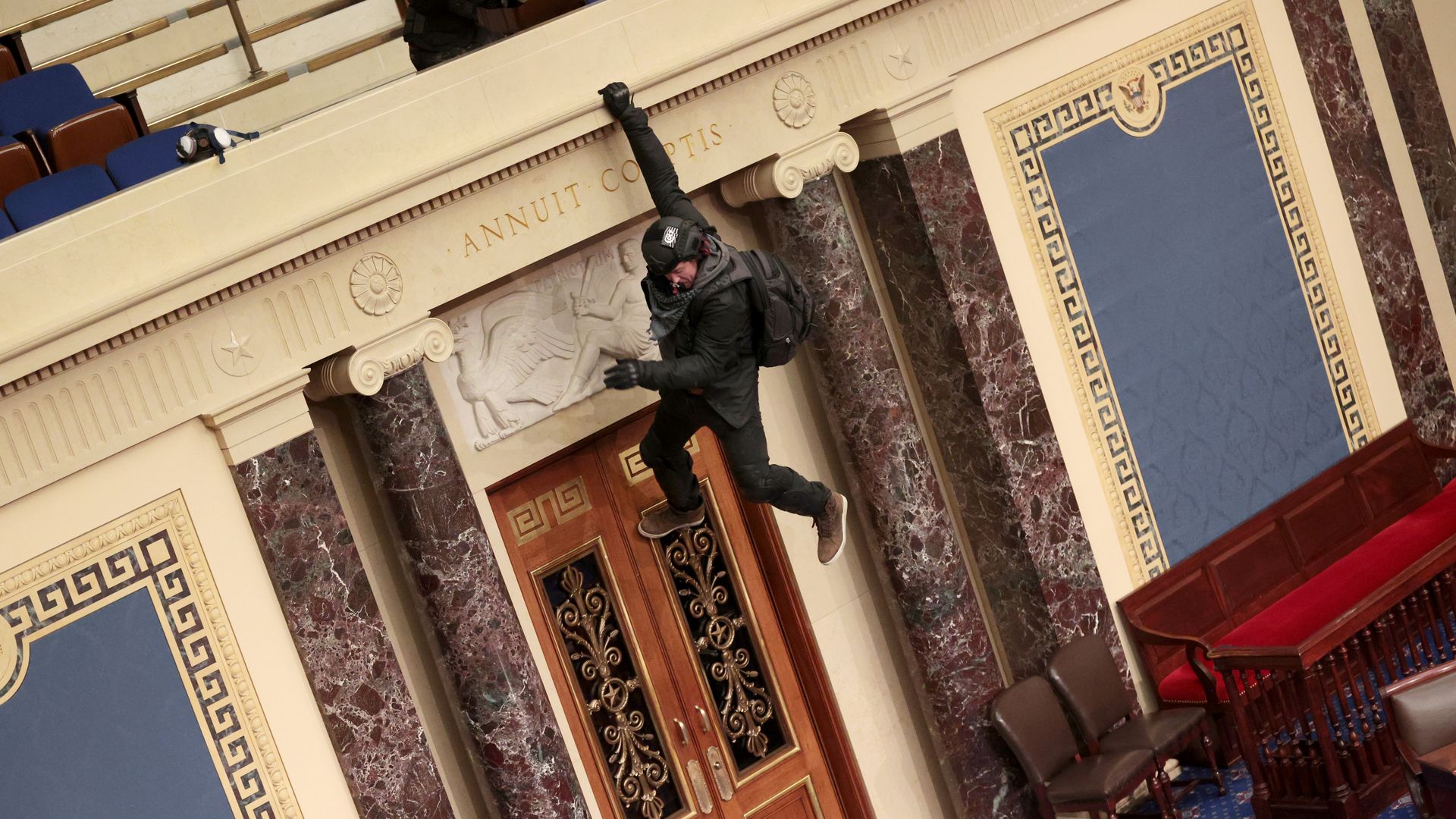 A rioter is seen hanging from the balcony in the U.S. Senate during the Jan. 6 Capitol assault.