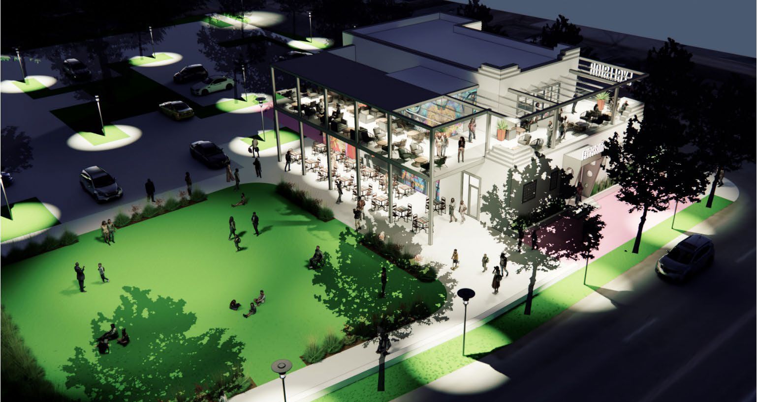 Night view of a modern two-story building with outdoor seating, people gathered on a green lawn, and a parking lot with illuminated street lamps.