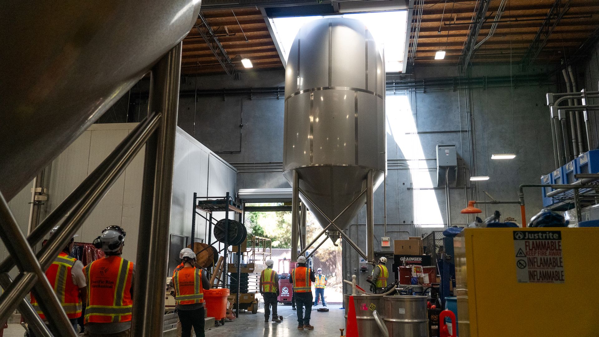 Workers watch as a 30-foot fermenter tank is craned in through a brewery skylight.