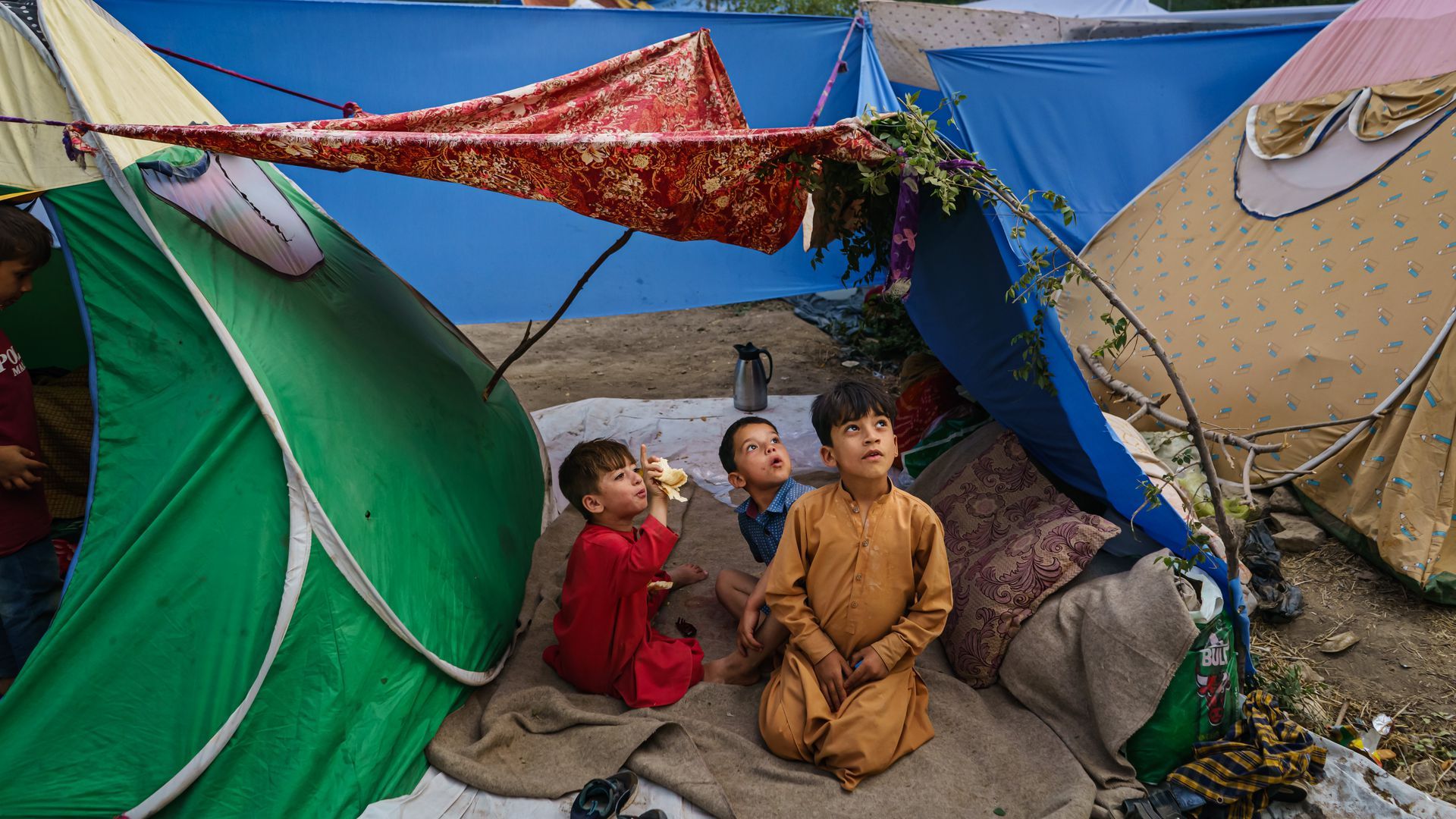 Children look at a passing aircraft at a makeshift camp for displaced Afghans on Saturday.