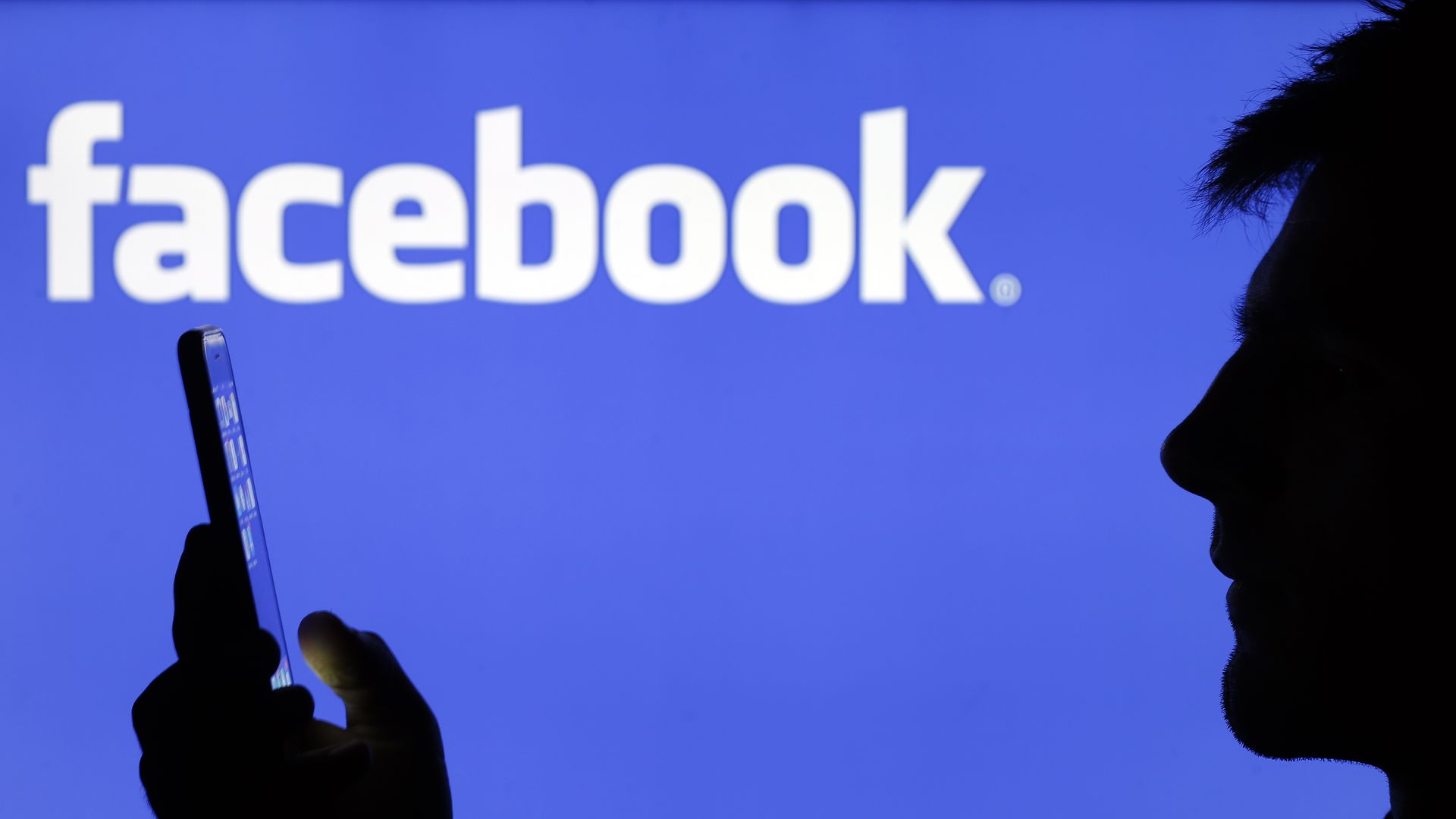A caricature of a man holds a phone with the facebook logo in the background.