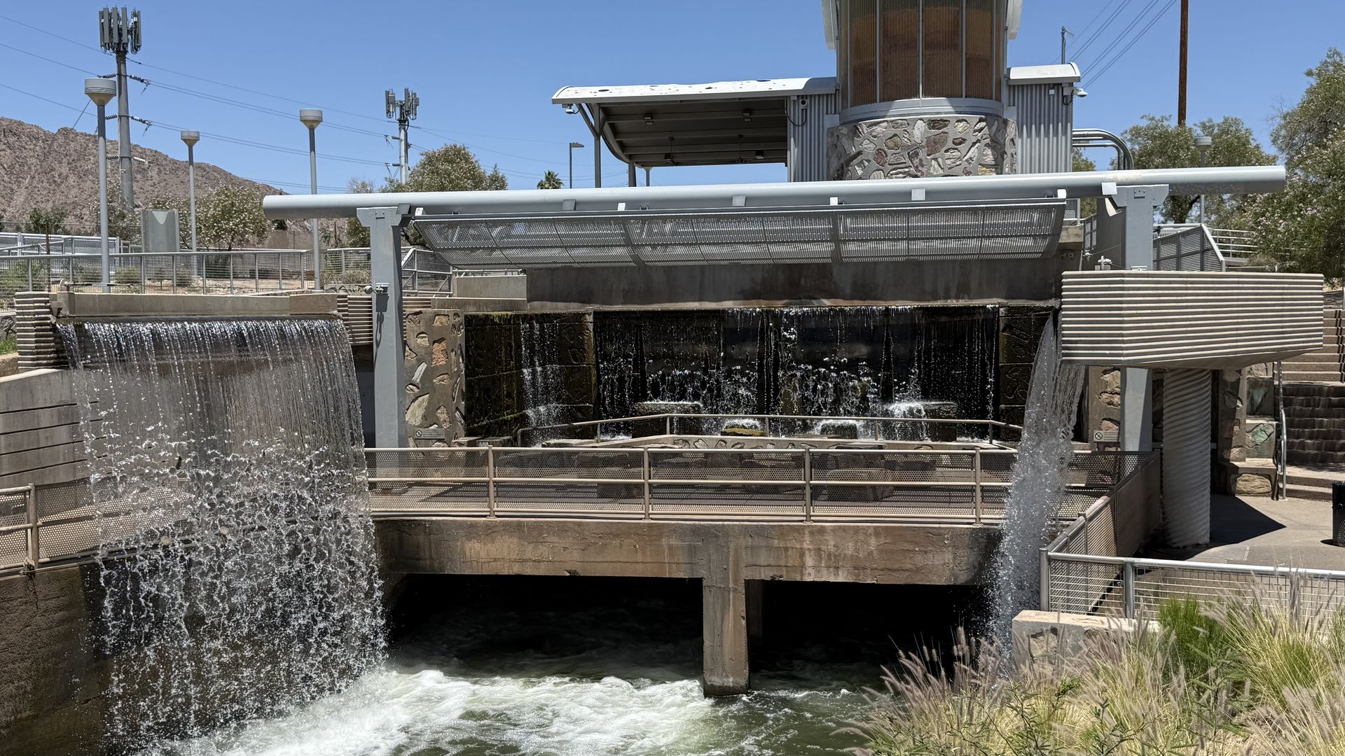 Waterfalls on three sides of an outdoor patio area above a canal. 