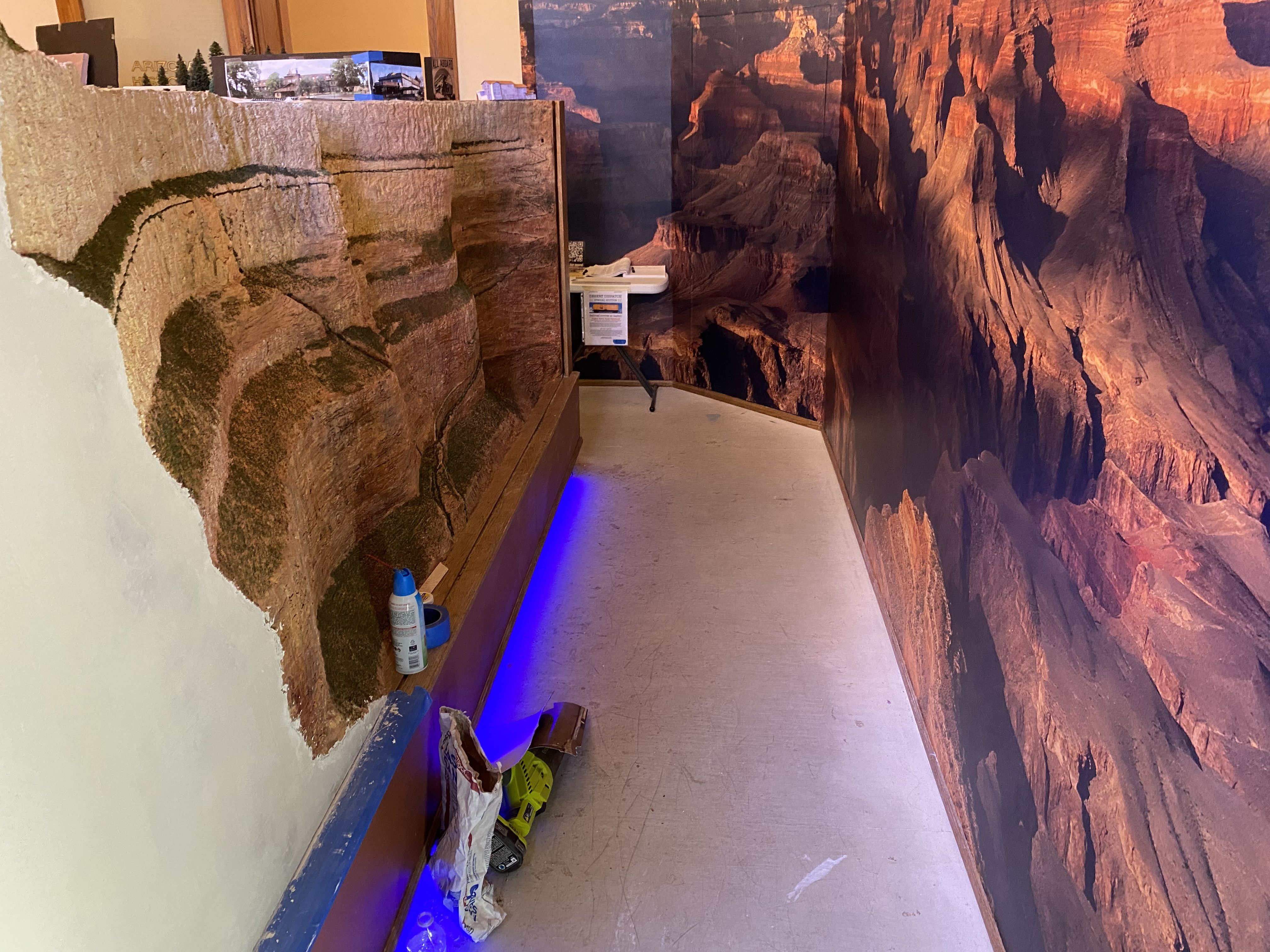 A partially incomplete plaster model of the south rim of the Grand Canyon facing a panoramic photo of the north rim