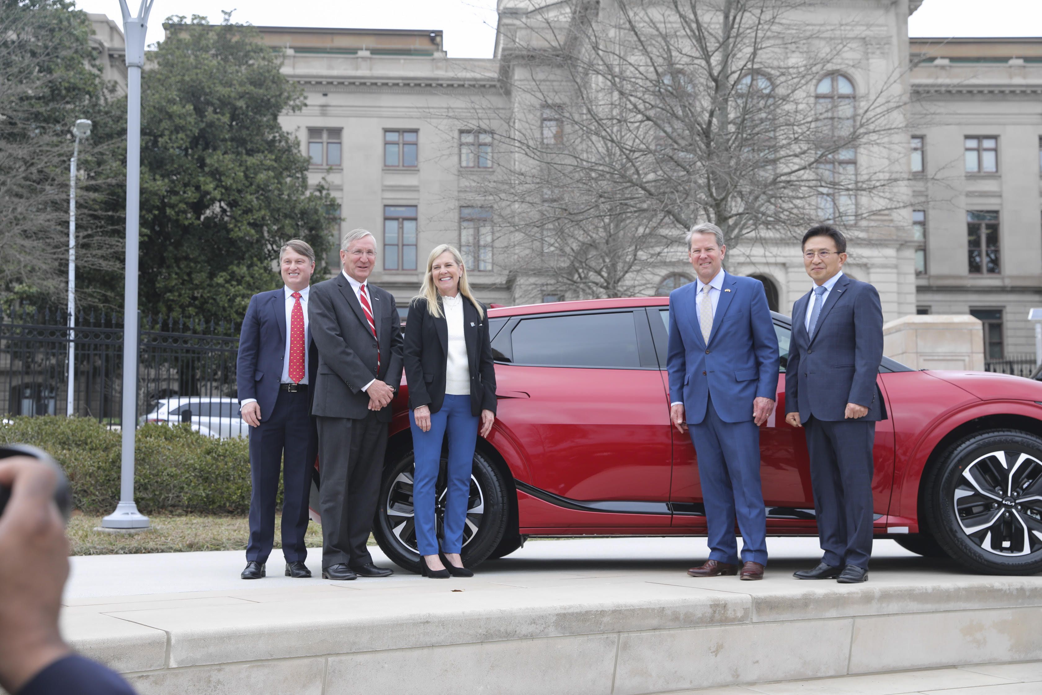 Group of people in front of a KIA car