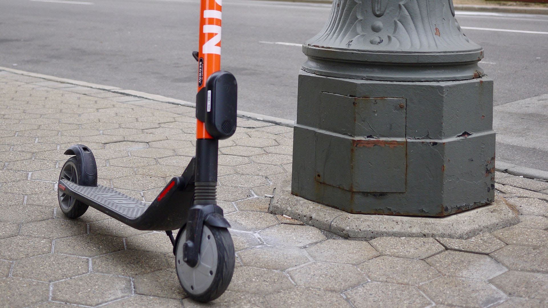 Spin scooter parked on a sidewalk.