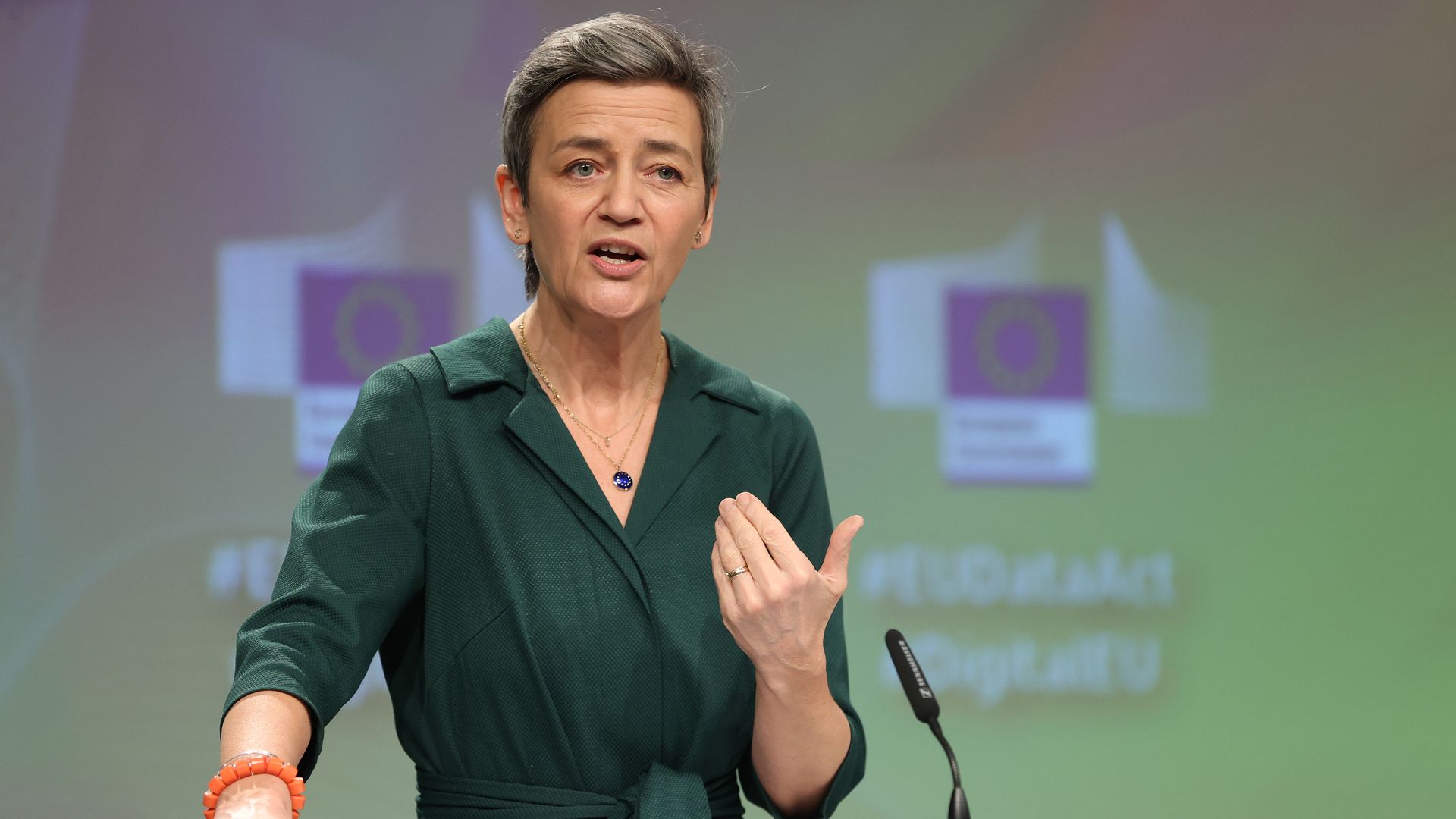 European Commission Executive Vice-President Margrethe Vestager in a green dress speaking at a podium