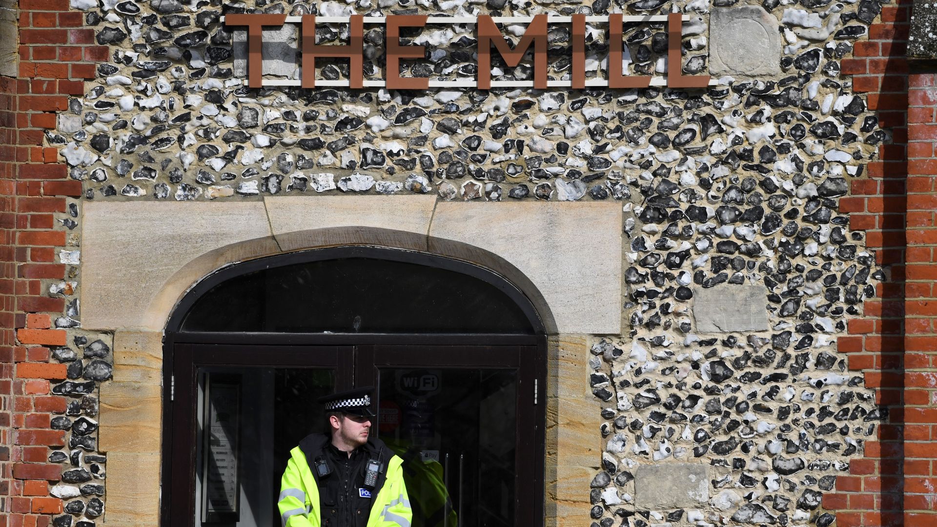 A police officer stands in front of the door of a pub in Salisbury, England.