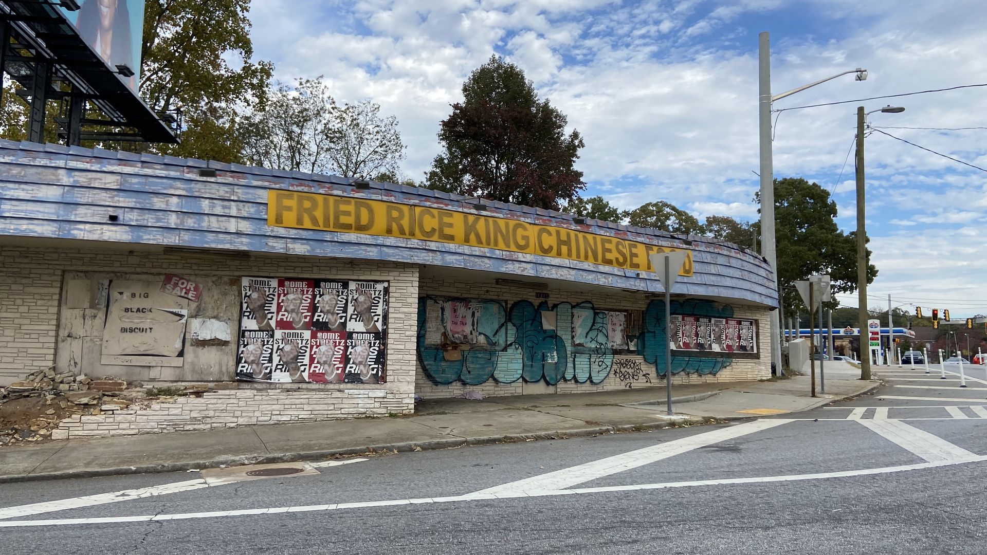 A photo of a squat building with a curved storefront that matches the curve of the road in front. The sign says “Fried Rice King Chinese Food.”