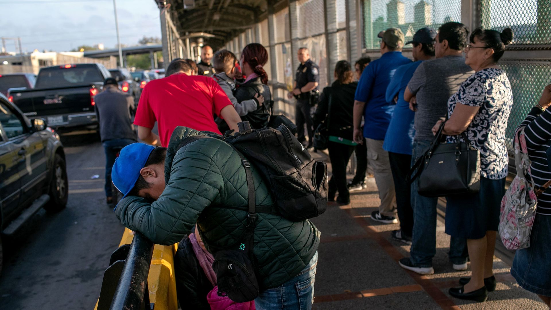 Photo of a person laying their head on a railing as they wait in line on a bridge