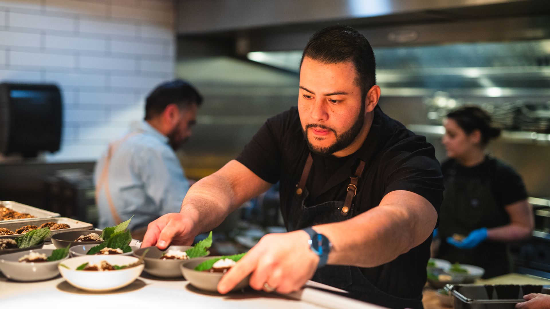 A man puts plates on a shelf inside a restaurant kitchen. 