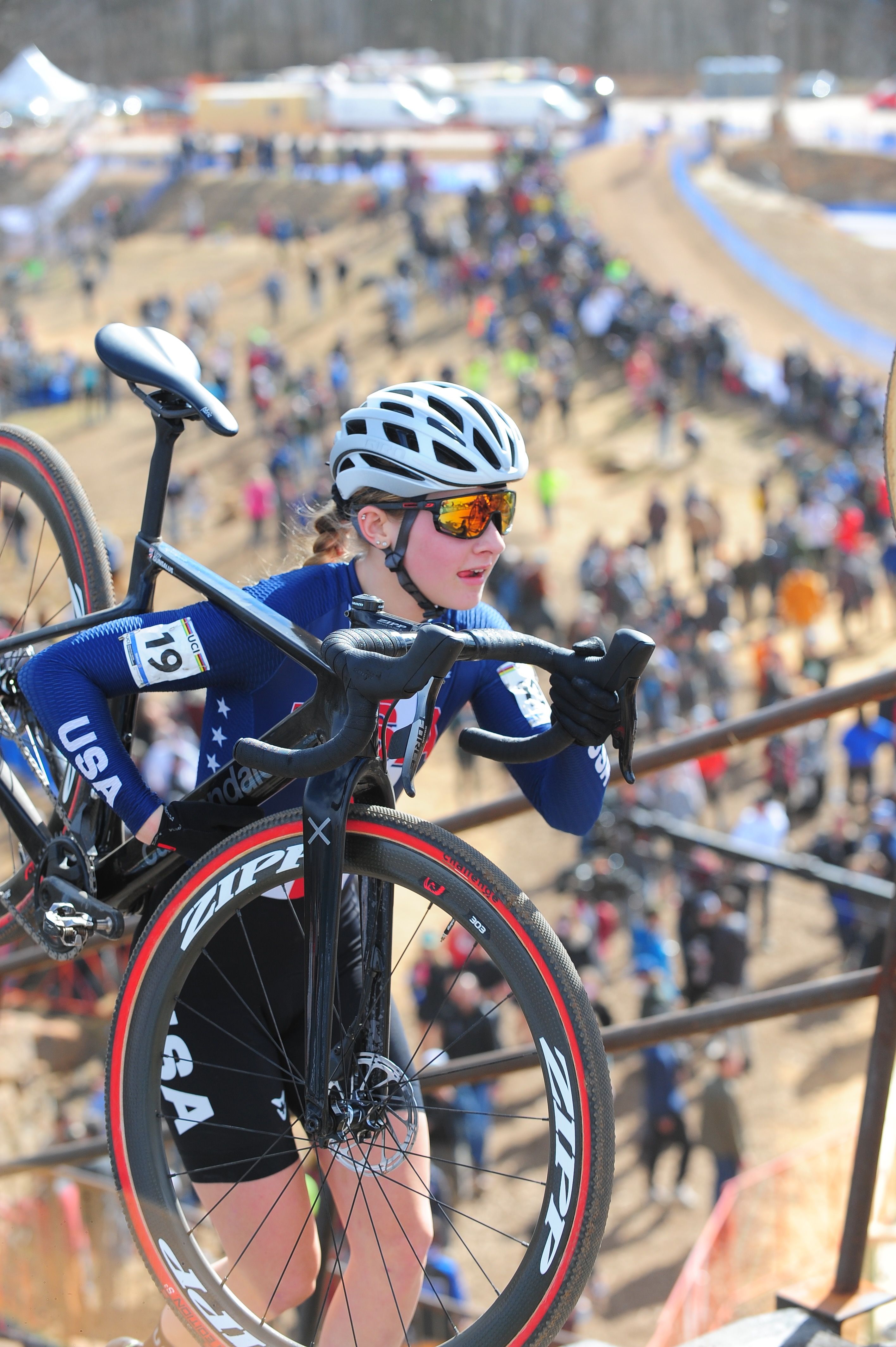 A woman carries her bike up the steps at a cyclo-cross event. 