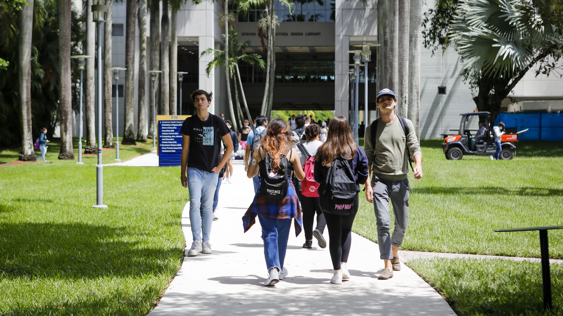 Students walk on a paved pathway through the campus of Florida International University. 