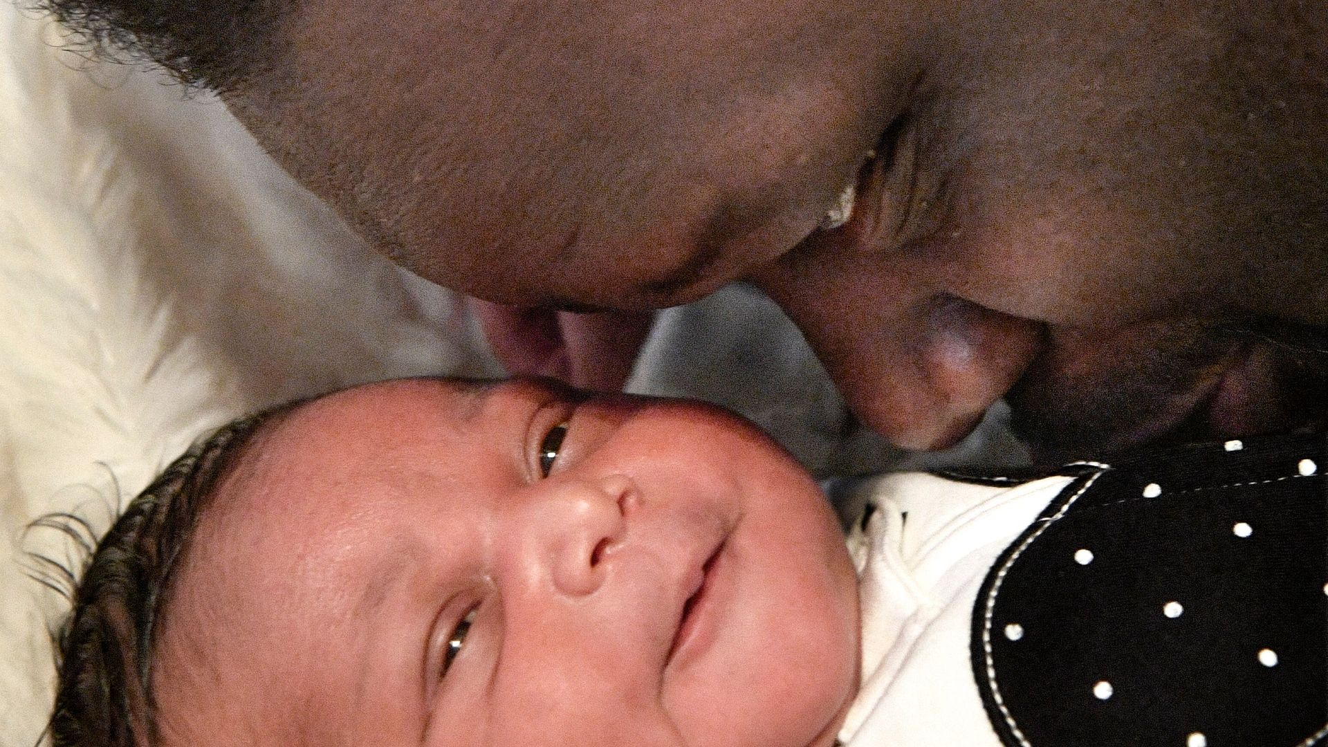 A proud father kisses a baby.