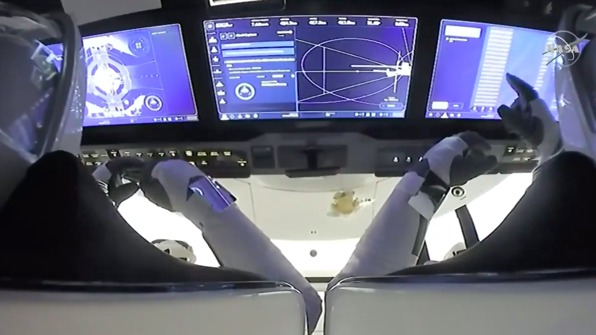 Two astronauts using a screen inside of the Crew Dragon vehicle