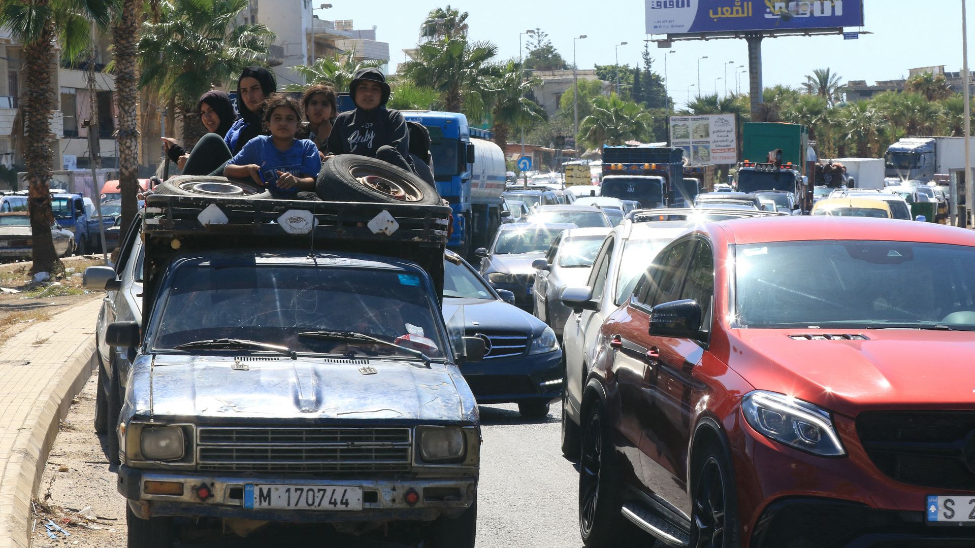 A family sits with their belongings in the back of a truck as they wait in a traffic jam in the southern Lebanese city of Sidon on September 23, 2024. 