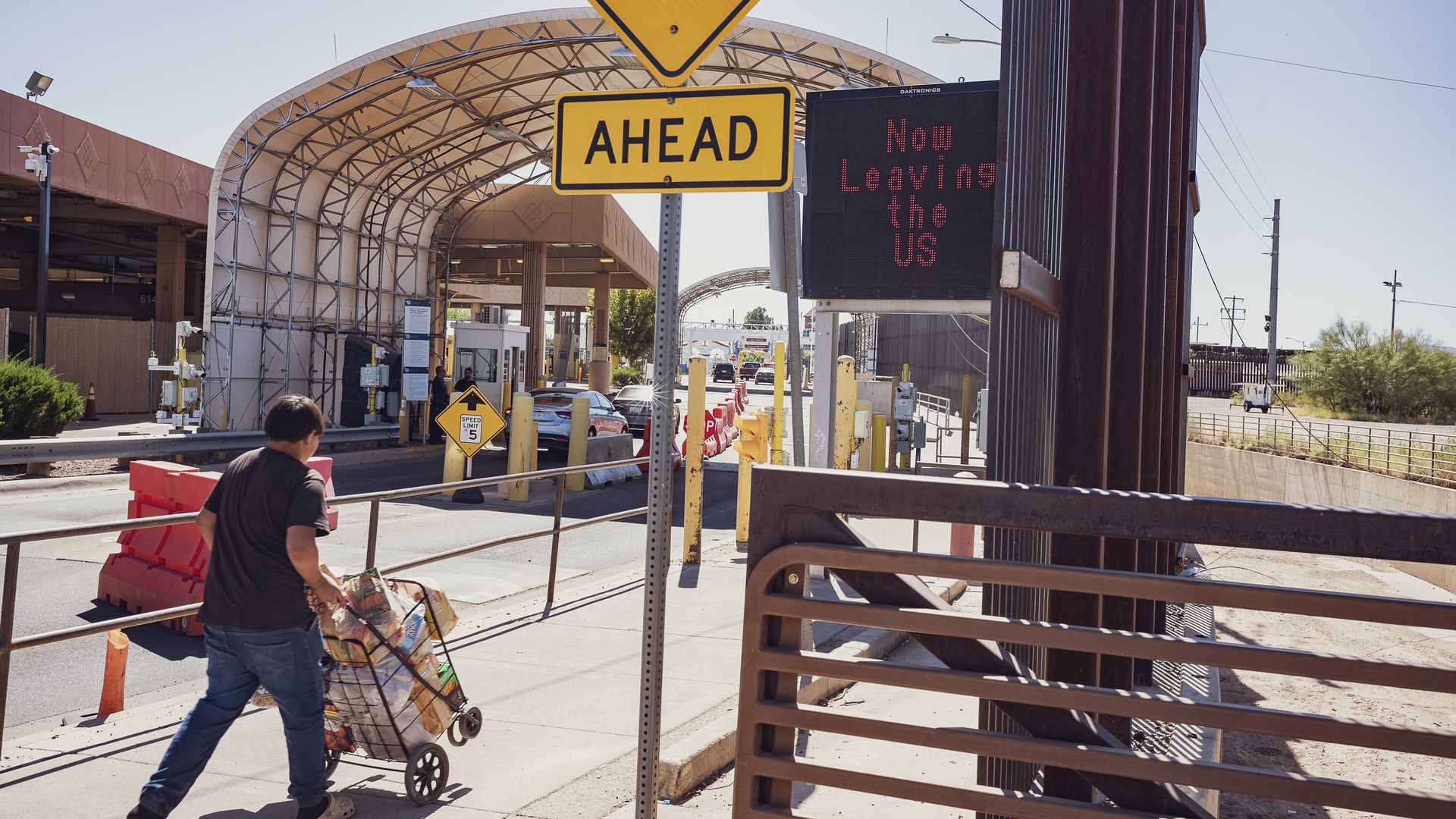 A person pushing a cart through a border crossing area.