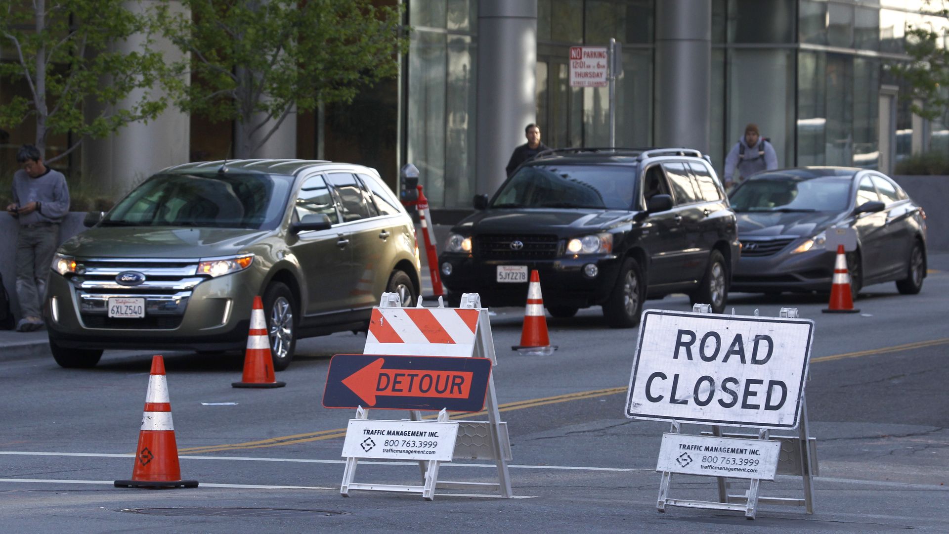 Photo of signs that say "Road closed" and "detour" on a road with cars
