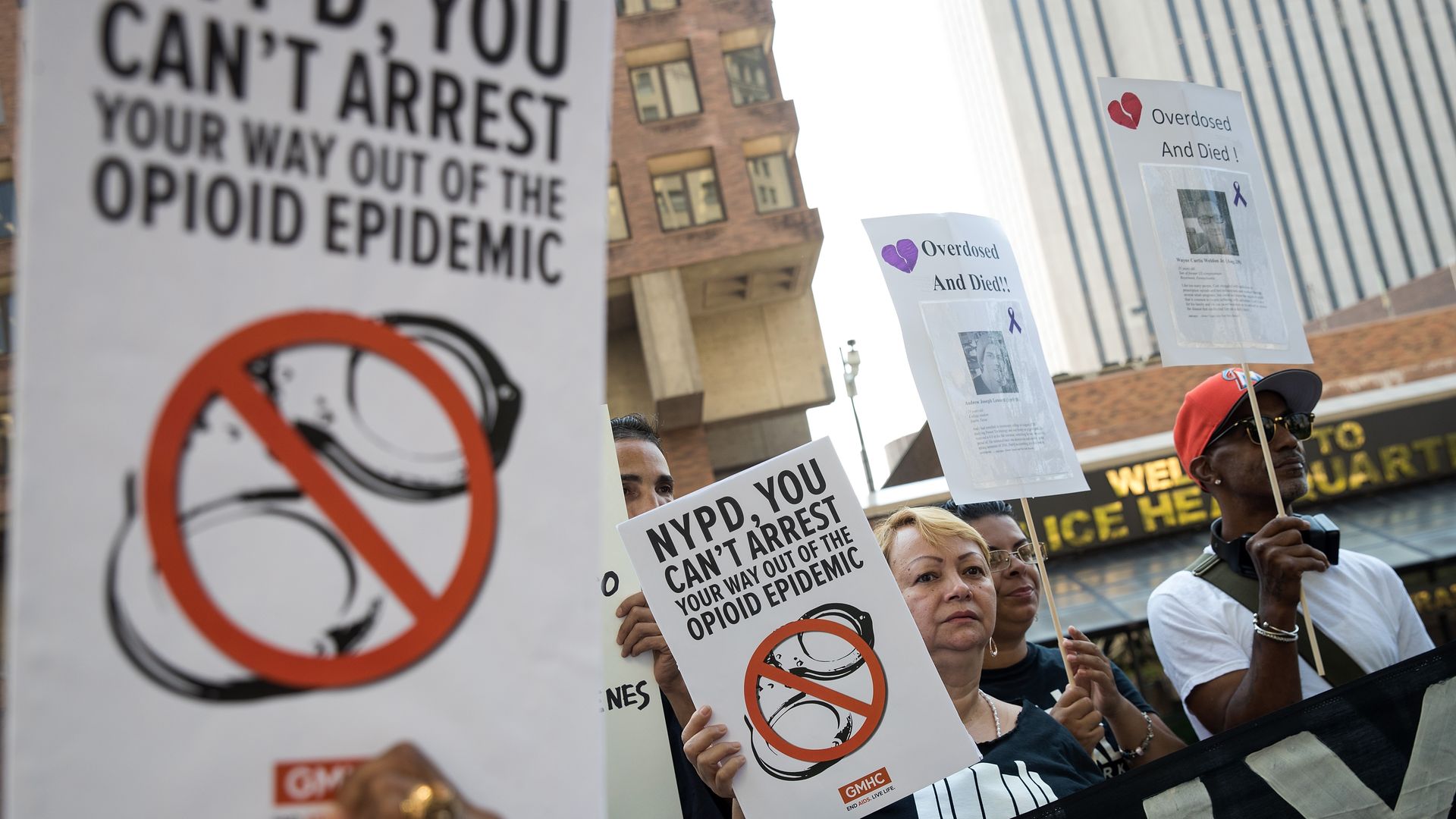 Protestors waving signs that say "You can't arrest your way out of the opioid epidemic"